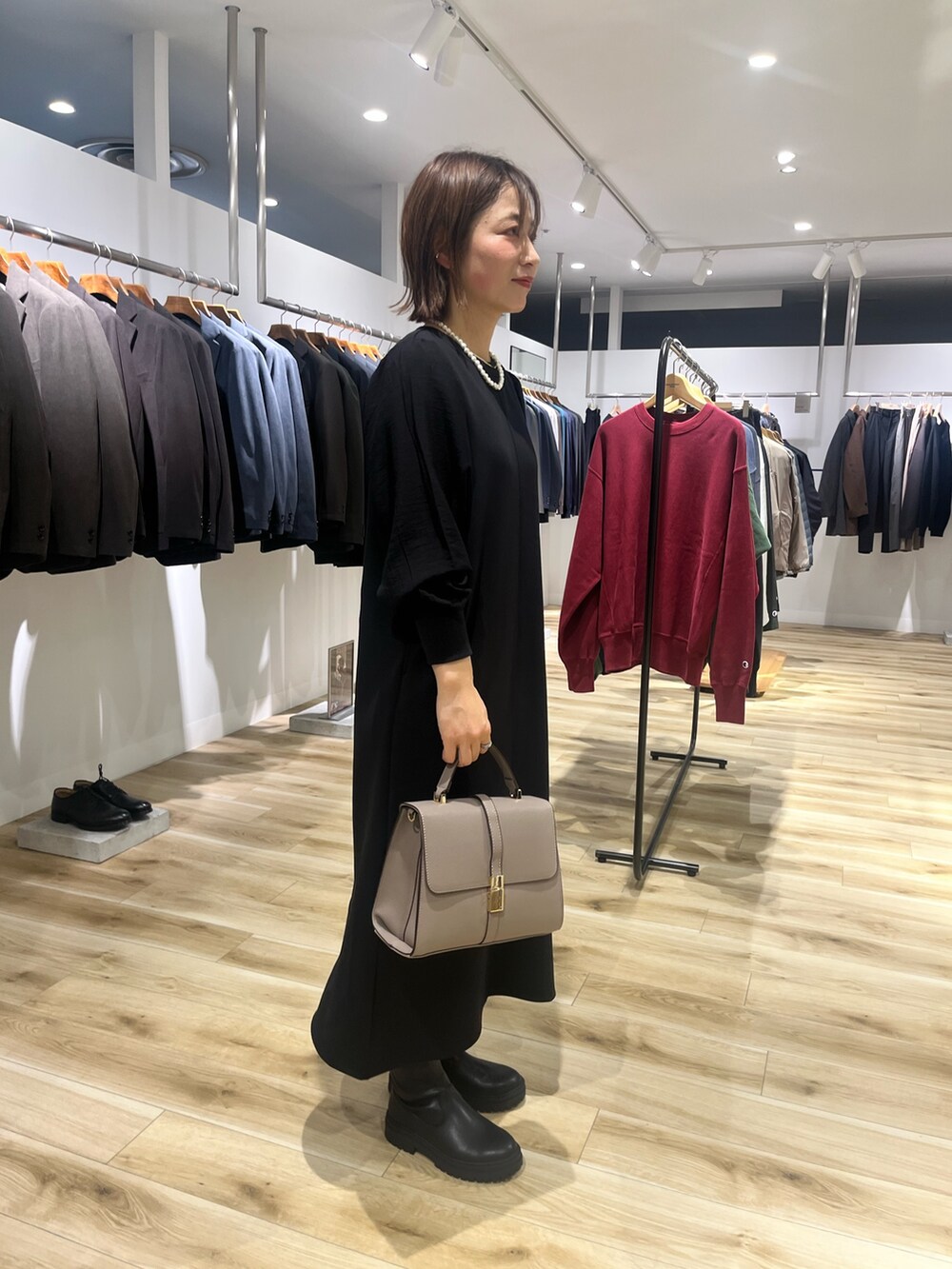 ブラック系のワンピース、グレー系のハンドバッグ、ブラック系のブーツを着用したレディースの秋コーディネートの2枚目の写真