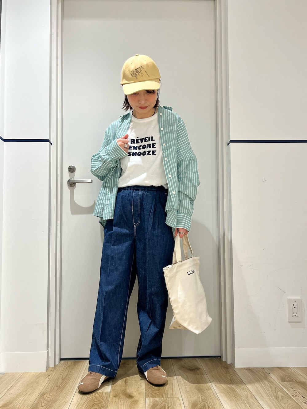 ブラウン系のスニーカー、ブルー系のデニムパンツ、ベージュ系のショルダーバッグを着用したレディースの春コーディネートの6枚目の写真