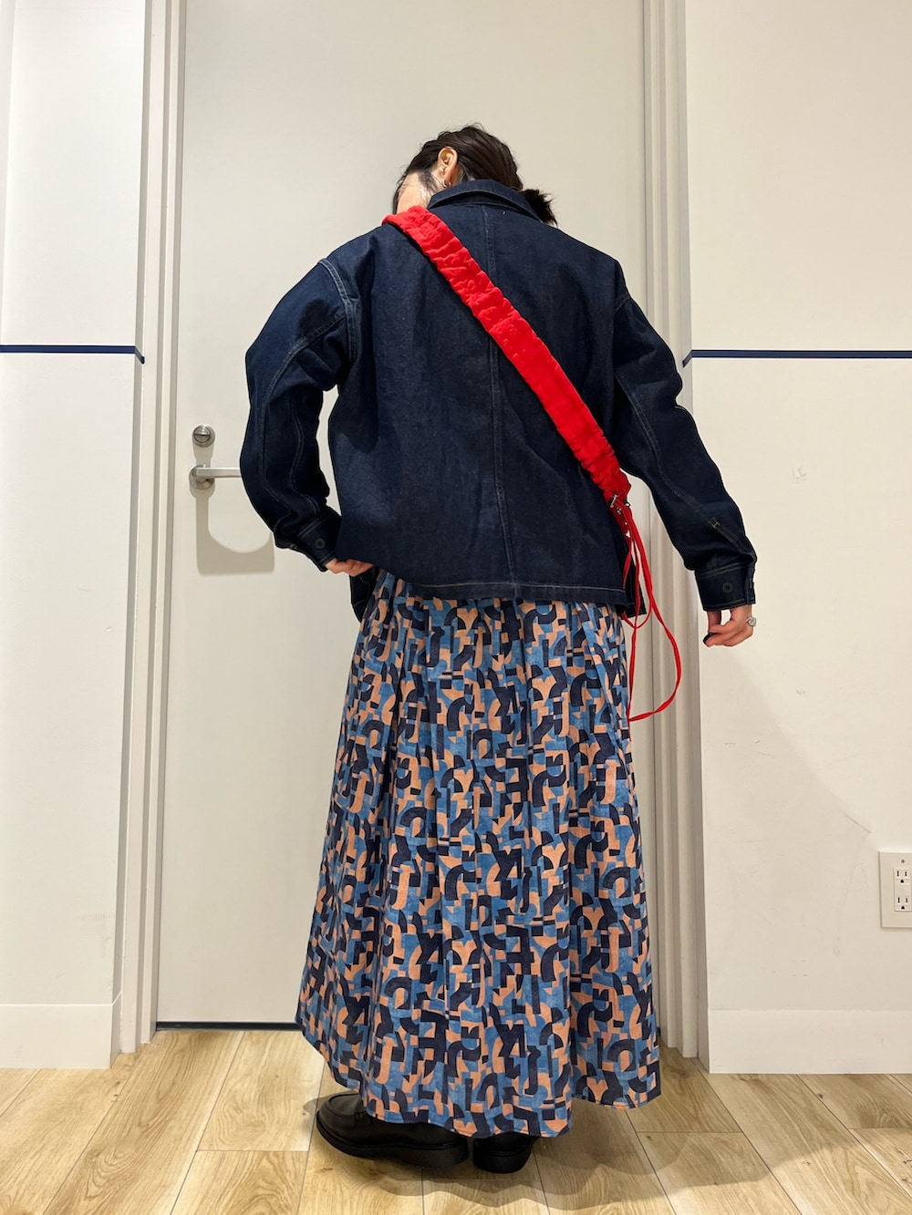 ブラック系のローファー、ブルー系のスカート、レッド系のショルダーバッグを着用したレディースの春コーディネートの4枚目の写真