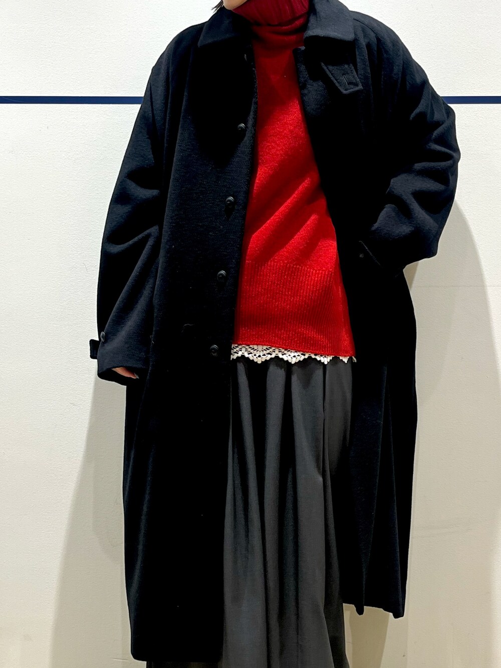レッド系のニット/セーター、ブラック系のステンカラーコート、ホワイト系のTシャツ/カットソーを着用したレディースの冬コーディネートの4枚目の写真