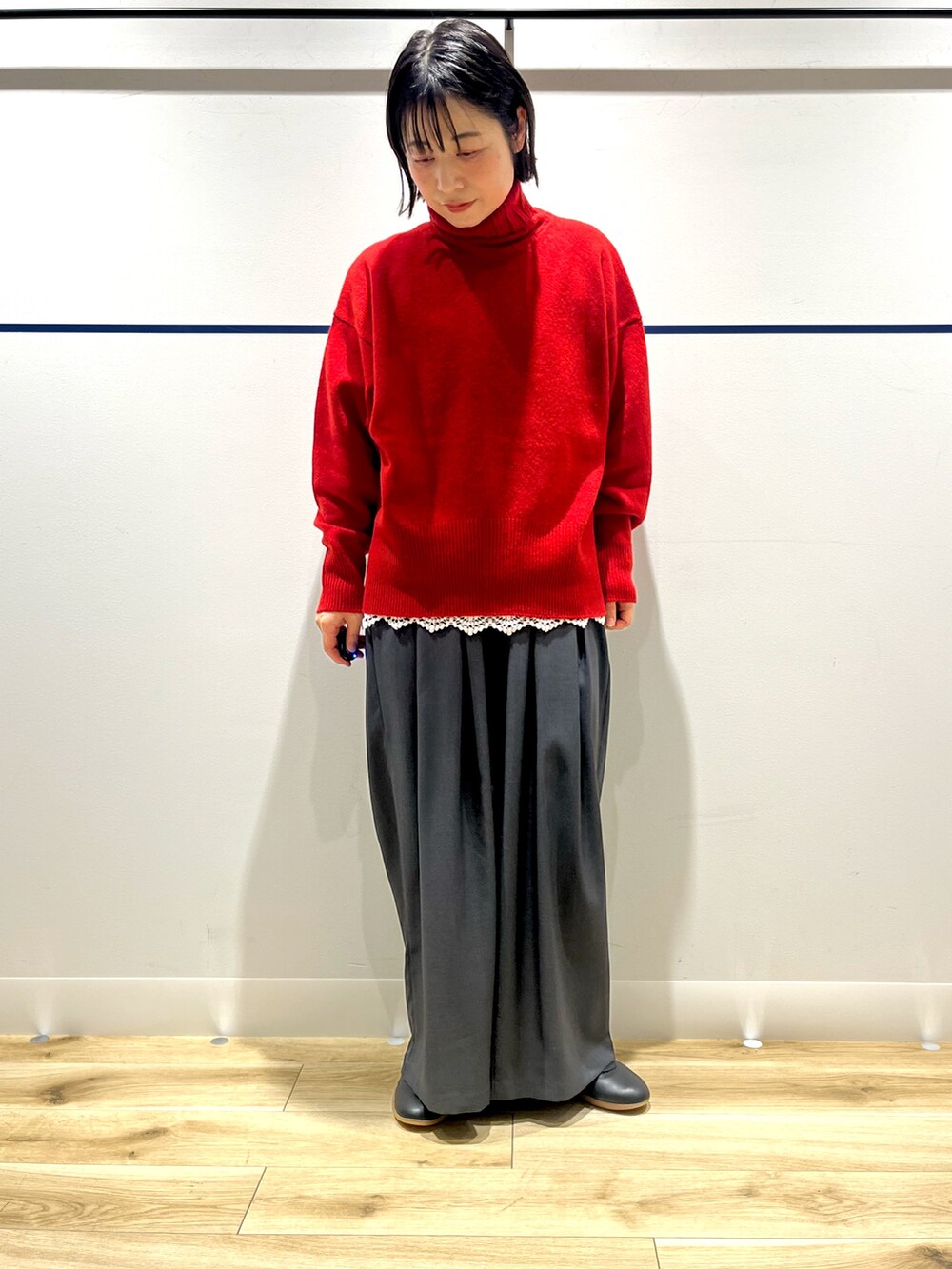 レッド系のニット/セーター、ブラック系のステンカラーコート、ホワイト系のTシャツ/カットソーを着用したレディースの冬コーディネートの6枚目の写真