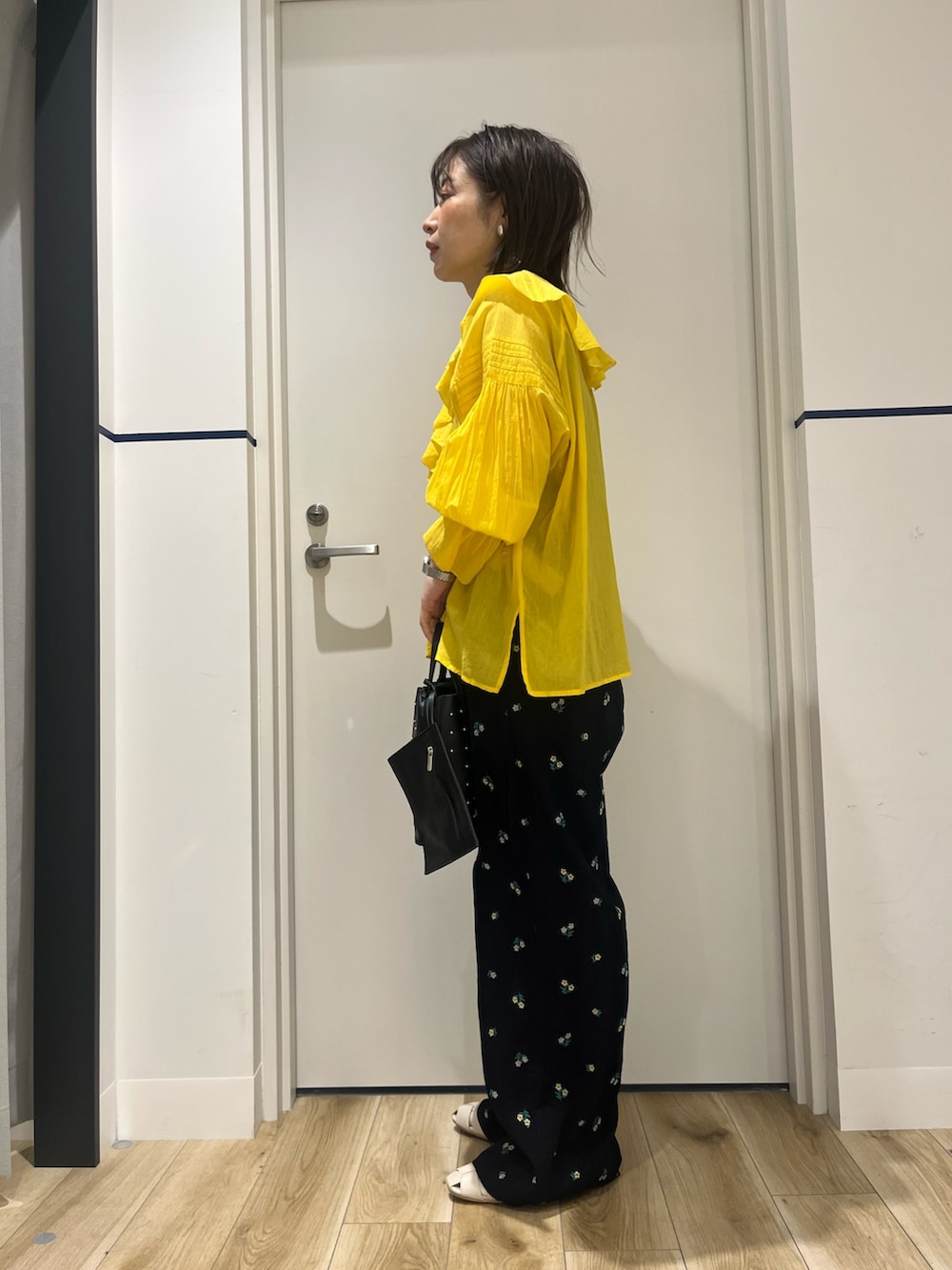 ブラック系のトートバッグ、ブルー系のその他パンツ、ホワイト系のパンプスを着用したレディースの春コーディネートの2枚目の写真