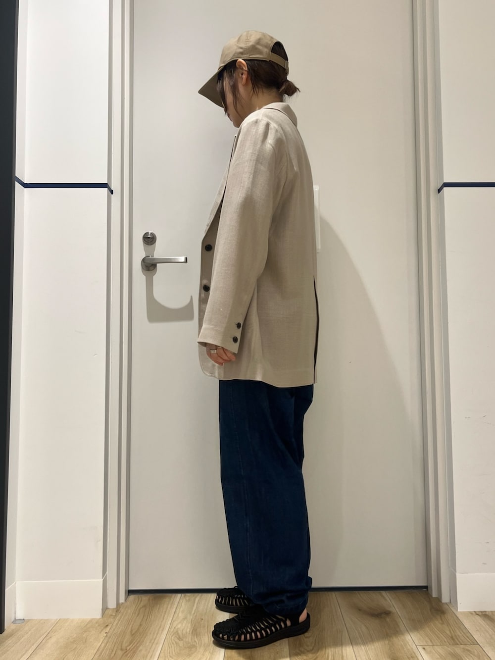 ブラック系のサンダル、ブルー系のデニムパンツ、レッド系のトートバッグを着用したレディースの春コーディネートの3枚目の写真
