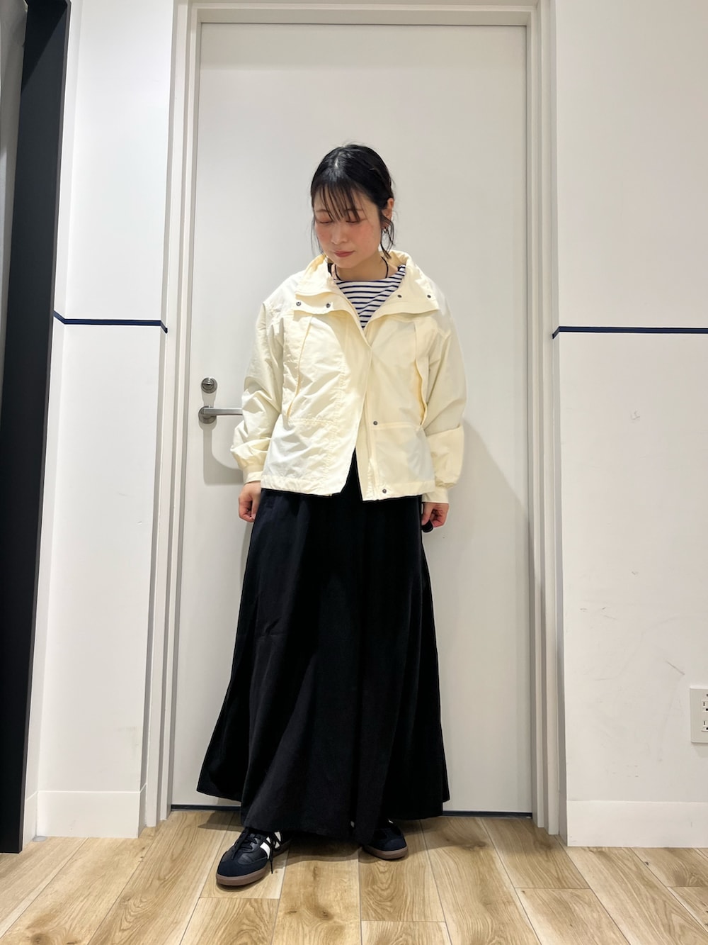 ブラック系のワンピース、ブラック系のスニーカー、ホワイト系のナイロンジャケットを着用したレディースの春コーディネートの4枚目の写真