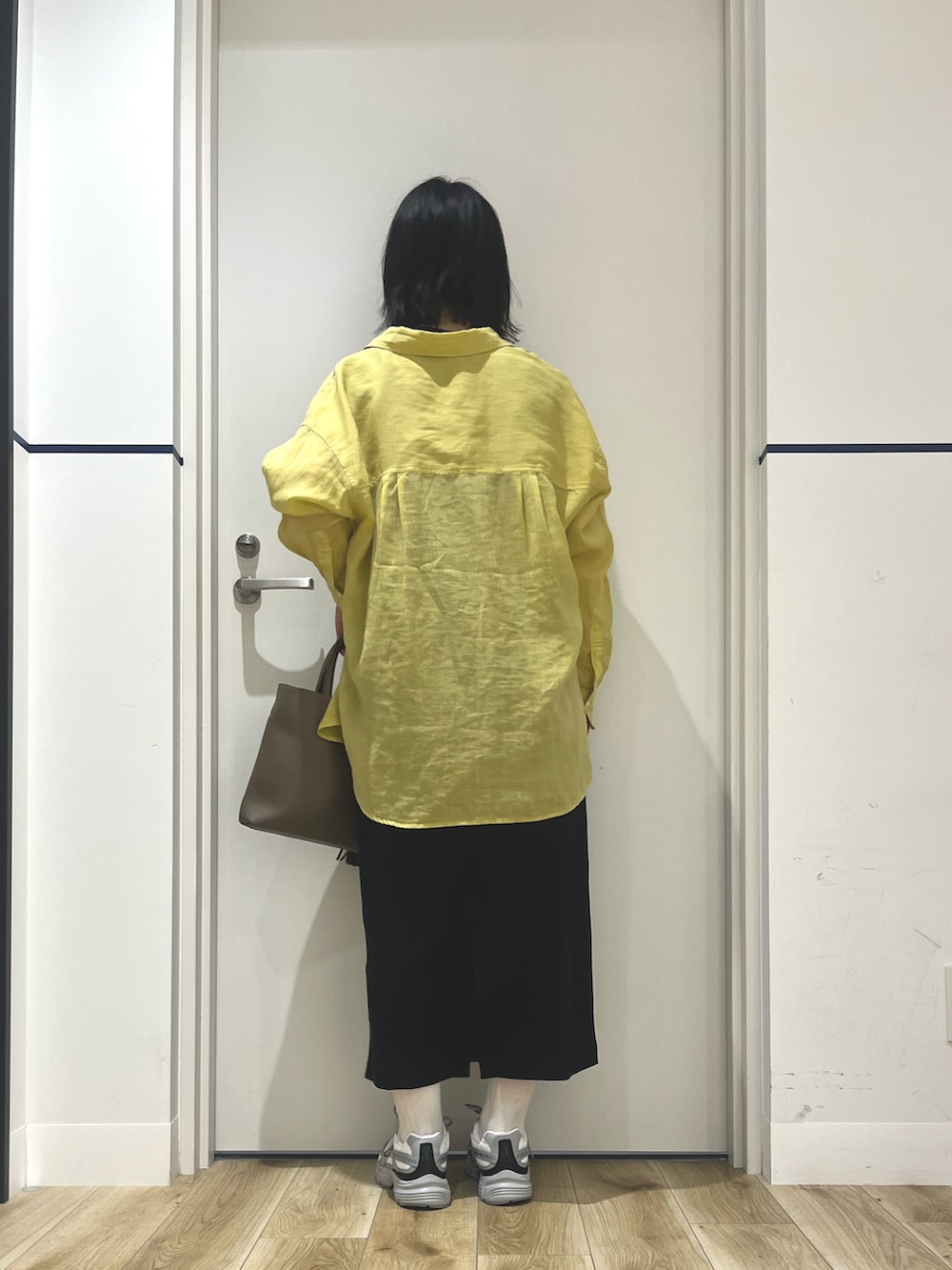 イエロー系のシャツ/ブラウス、ブラック系のワンピース、グレー系のスニーカーを着用したレディースの夏コーディネートの2枚目の写真