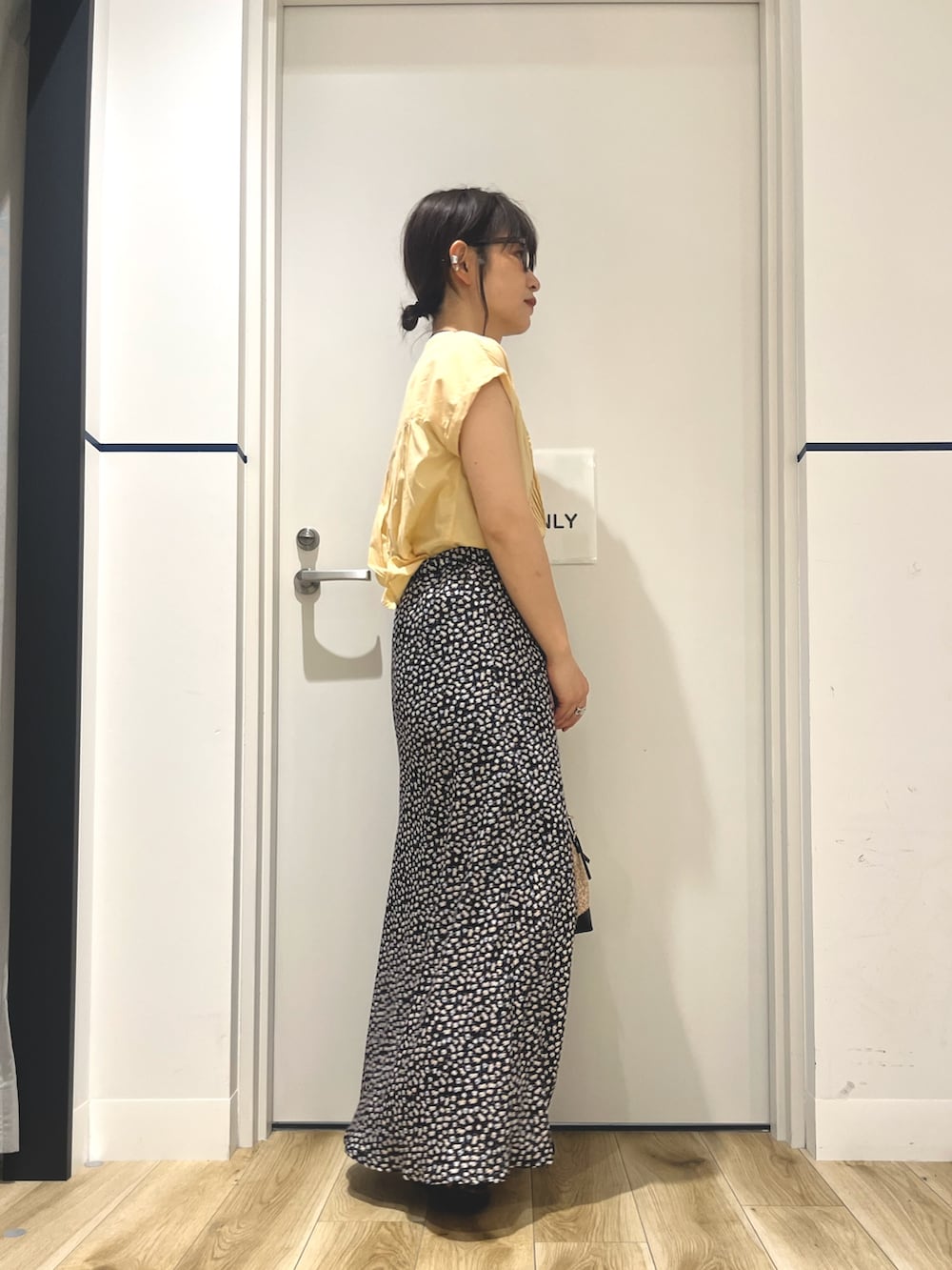 イエロー系のシャツ/ブラウス、ホワイト系のスカート、ブラック系のショルダーバッグを着用したレディースの夏コーディネートの2枚目の写真