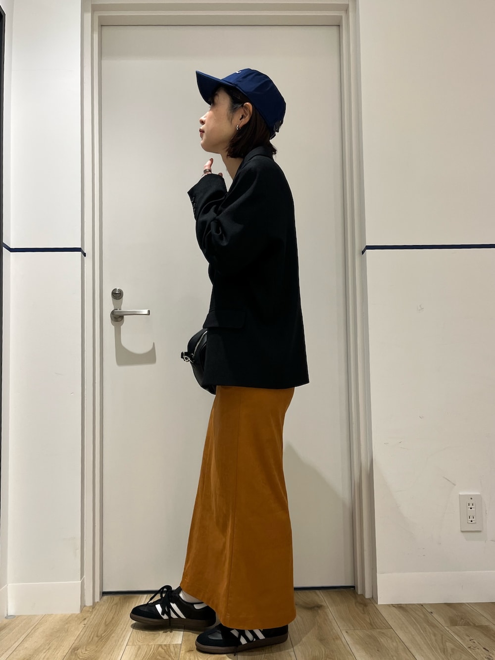 ブラック系のショルダーバッグ、ブラック系のその他アウター、ブラウン系のスカートを着用したレディースの春コーディネートの2枚目の写真