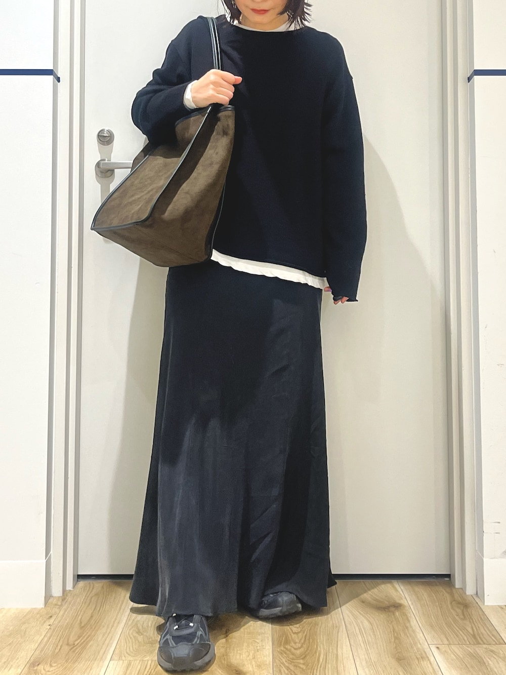 ブラック系のニット/セーター、グリーン系のトートバッグ、ホワイト系のTシャツ/カットソーを着用したレディースの秋コーディネートの3枚目の写真