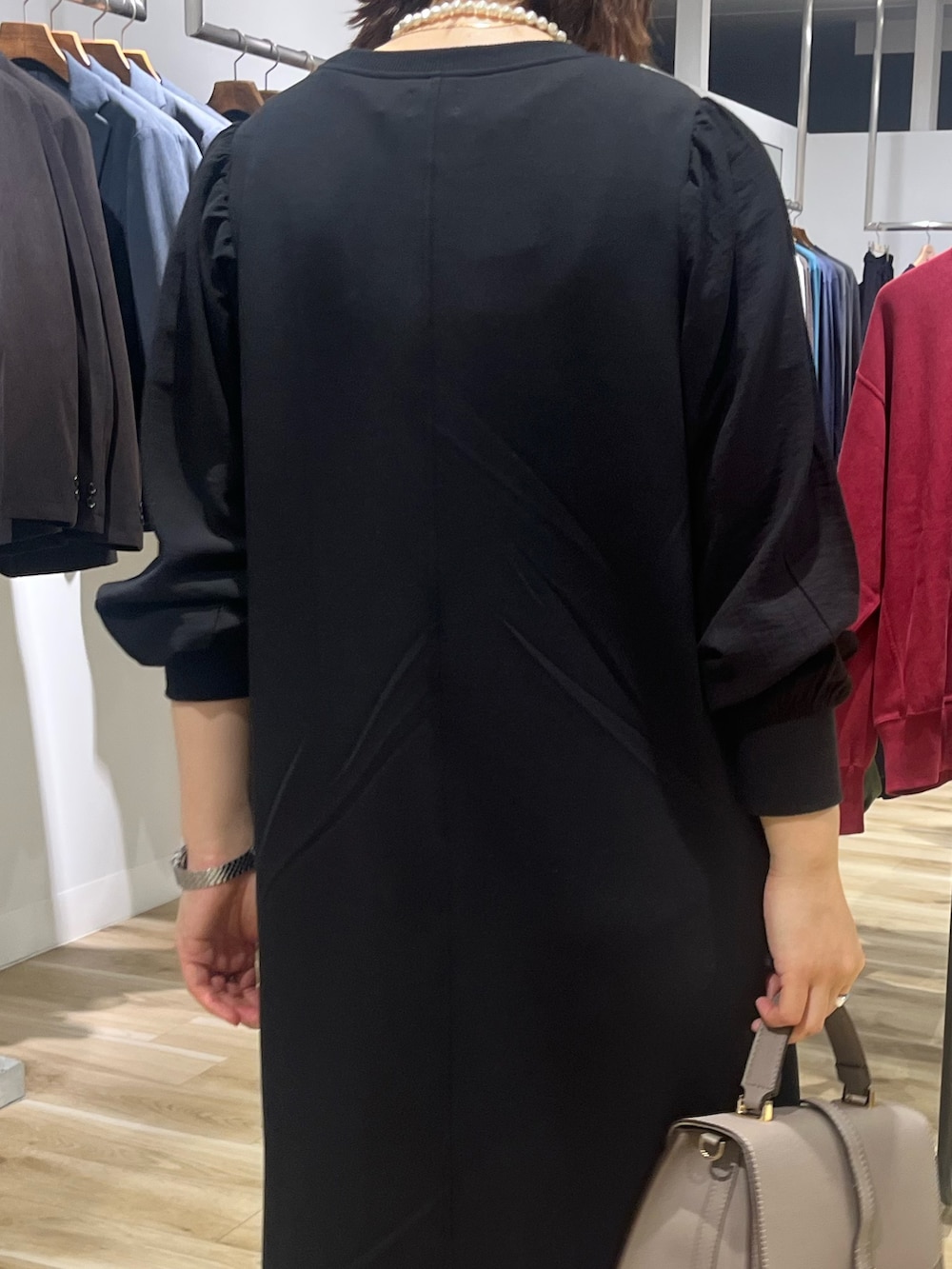 ブラック系のワンピース、グレー系のハンドバッグ、ブラック系のブーツを着用したレディースの秋コーディネートの6枚目の写真