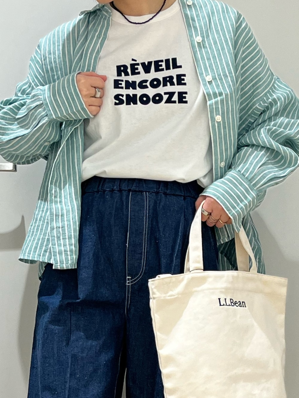 ブラウン系のスニーカー、ブルー系のデニムパンツ、ベージュ系のショルダーバッグを着用したレディースの春コーディネートの4枚目の写真