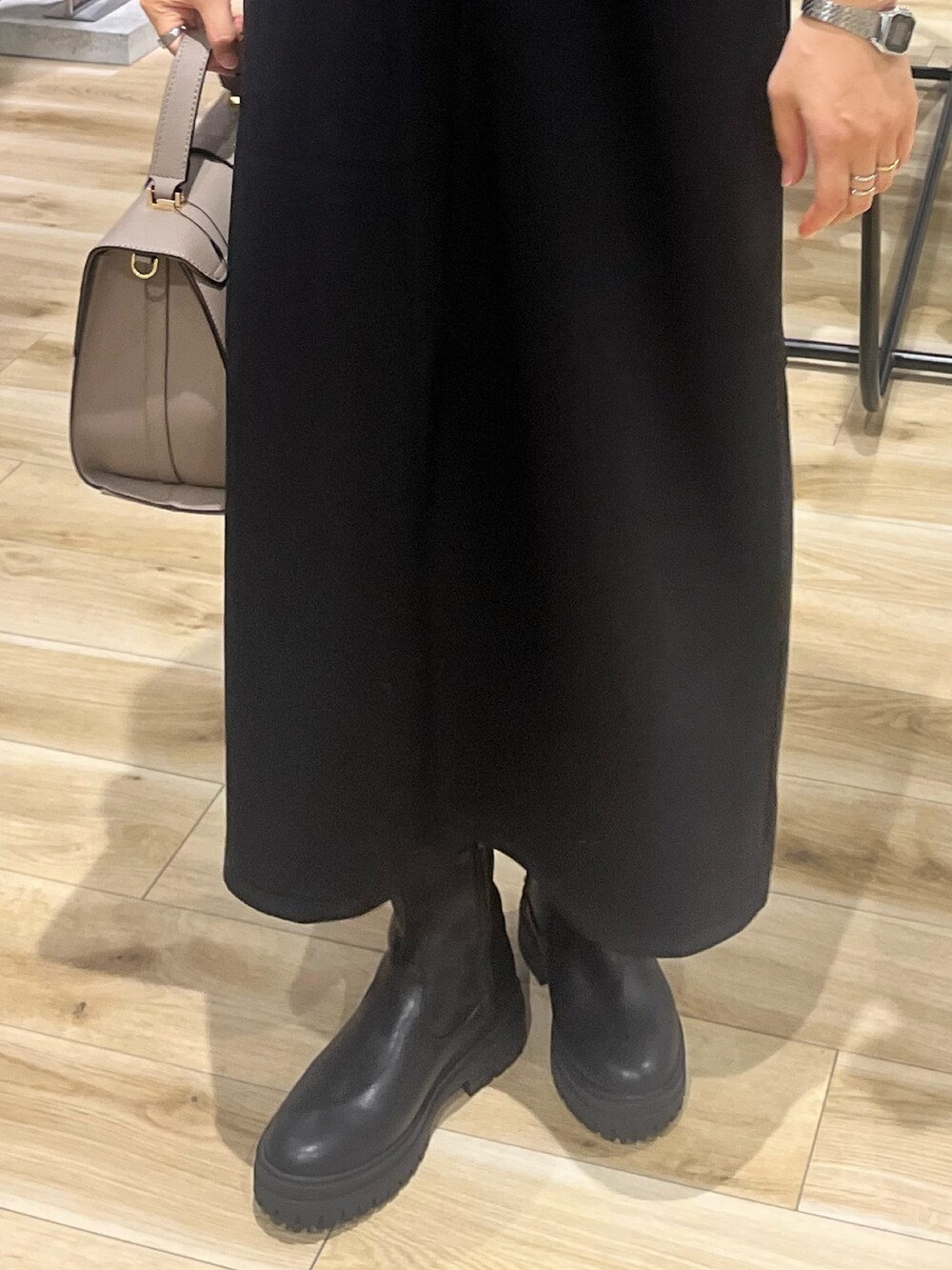 ブラック系のワンピース、グレー系のハンドバッグ、ブラック系のブーツを着用したレディースの秋コーディネートの4枚目の写真