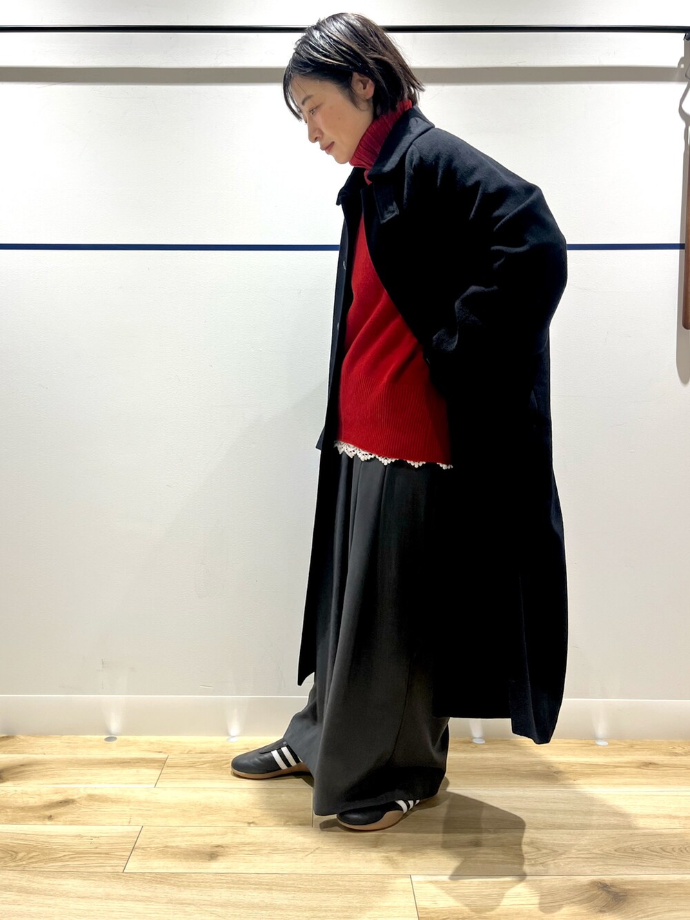 レッド系のニット/セーター、ブラック系のステンカラーコート、ホワイト系のTシャツ/カットソーを着用したレディースの冬コーディネートの3枚目の写真