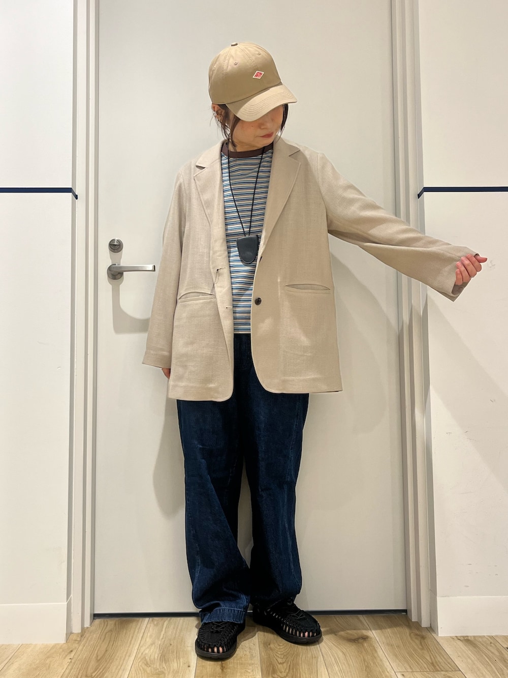 ブラック系のサンダル、ブルー系のデニムパンツ、レッド系のトートバッグを着用したレディースの春コーディネートの2枚目の写真