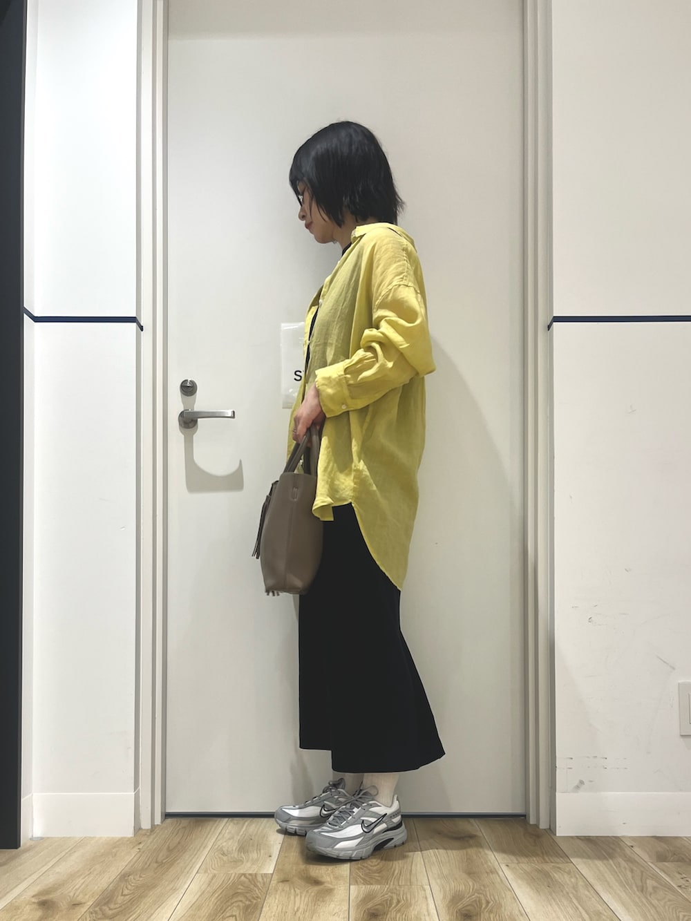 イエロー系のシャツ/ブラウス、ブラック系のワンピース、グレー系のスニーカーを着用したレディースの夏コーディネートの3枚目の写真