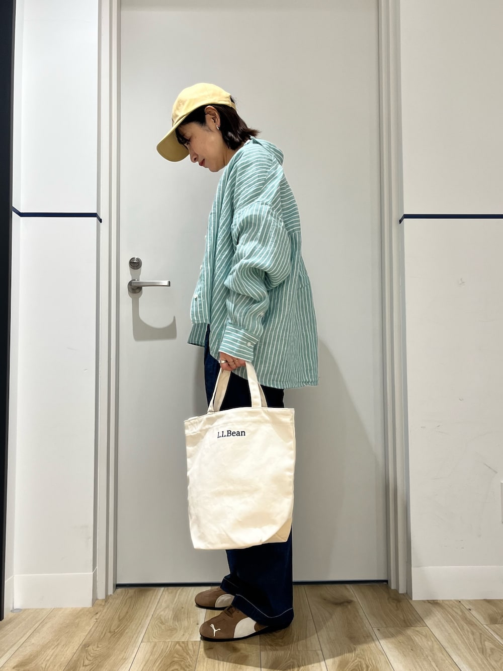 ブラウン系のスニーカー、ブルー系のデニムパンツ、ベージュ系のショルダーバッグを着用したレディースの春コーディネートの2枚目の写真