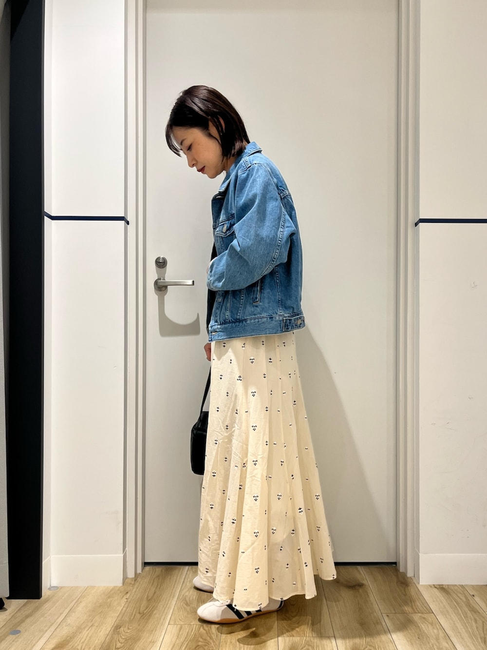 ブラック系のボストンバッグ、ホワイト系のスカート、ホワイト系のスニーカーを着用したレディースの春コーディネートの2枚目の写真