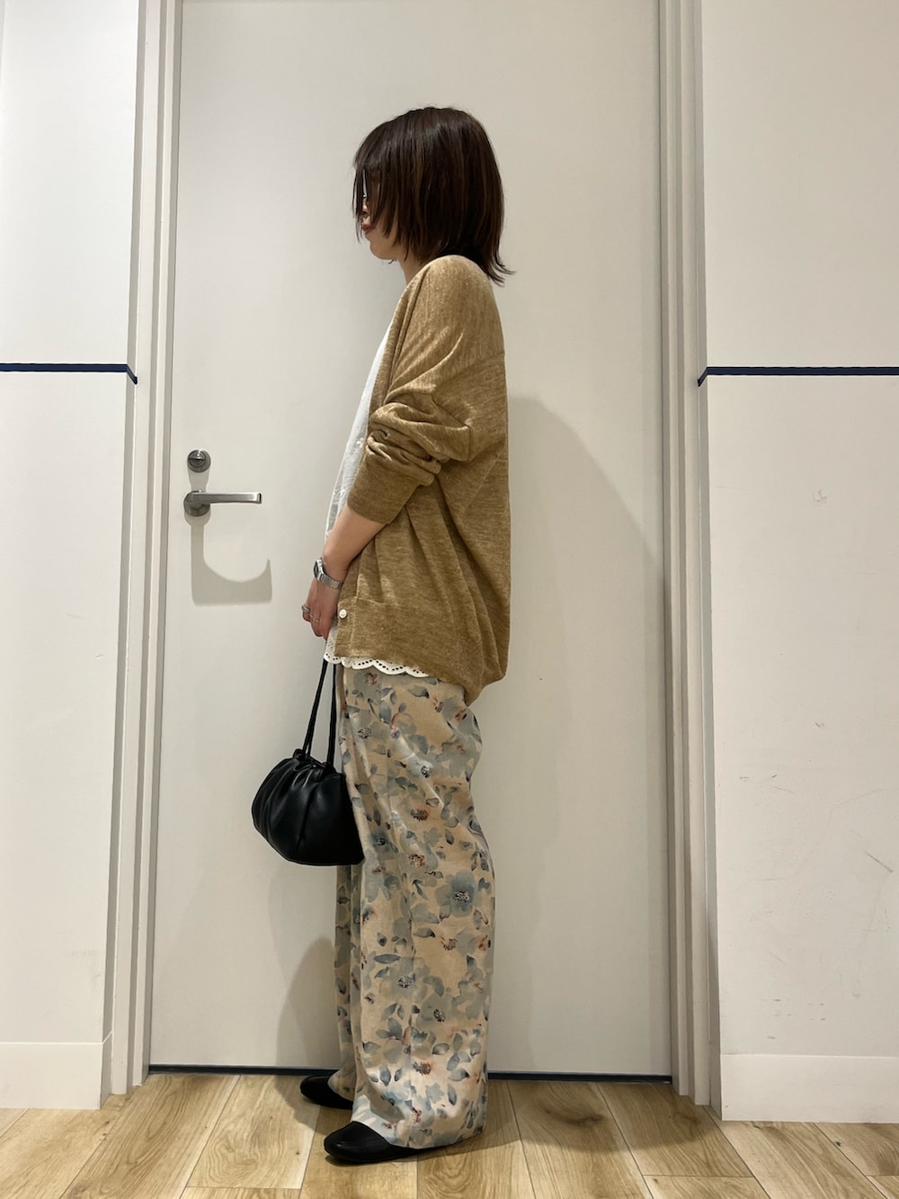 ベージュ系のカーディガン/ボレロ、ホワイト系のシャツ/ブラウス、ブラック系のショルダーバッグを着用したレディースの春コーディネートの2枚目の写真