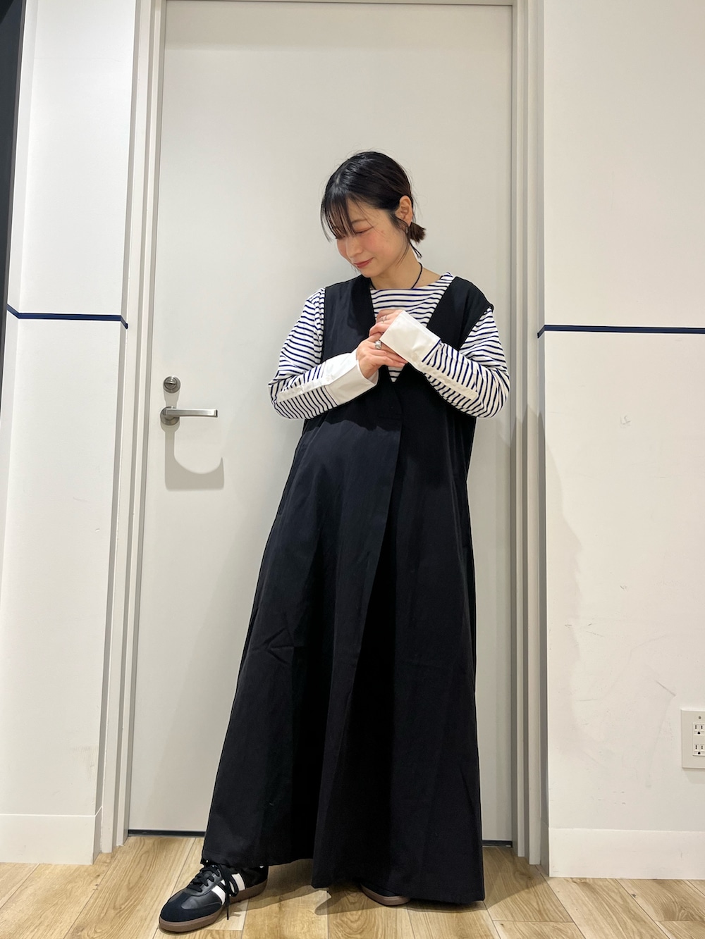 ブラック系のワンピース、ブラック系のスニーカー、ホワイト系のナイロンジャケットを着用したレディースの春コーディネートの5枚目の写真