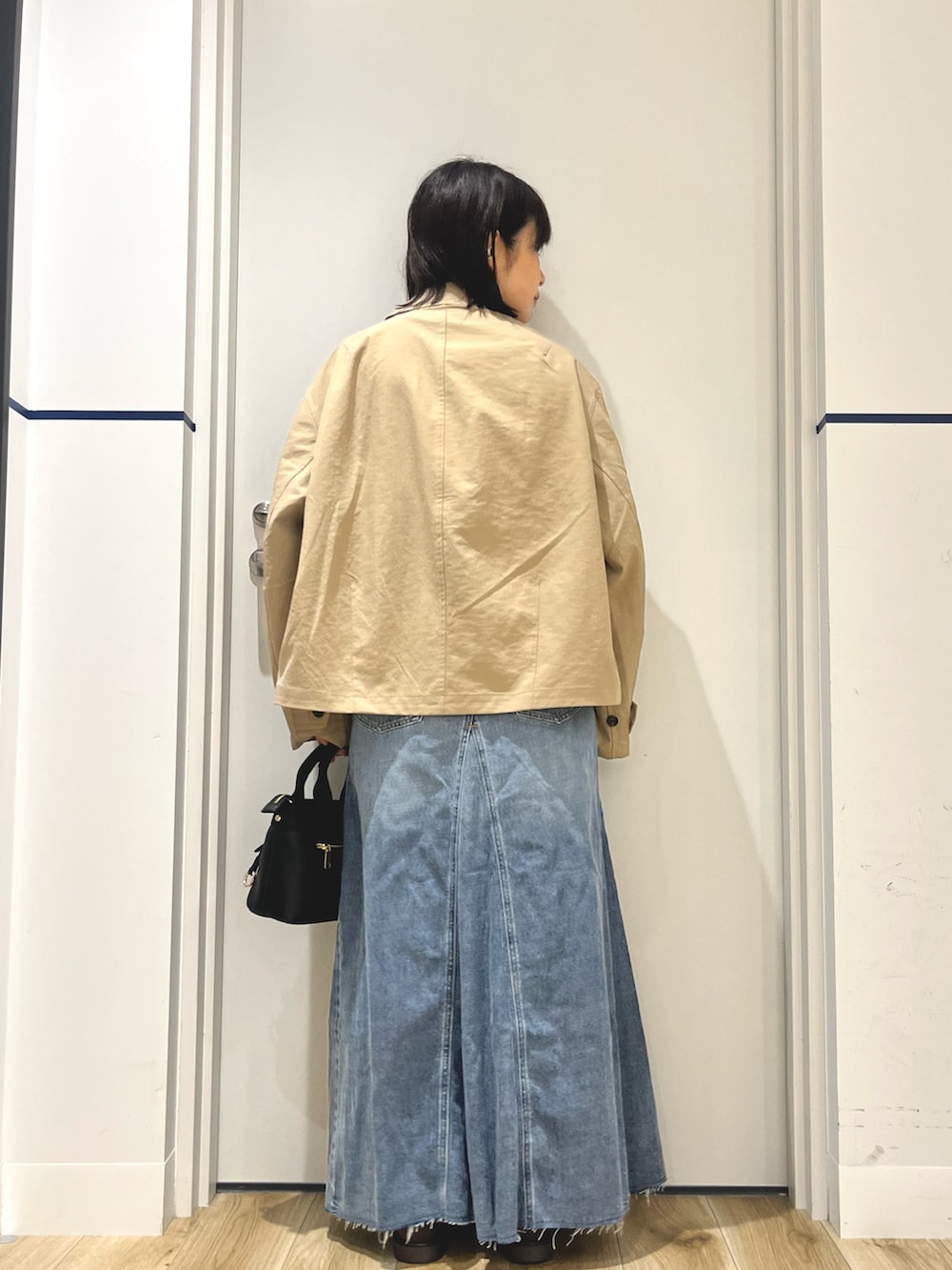 ブラウン系のローファー、ブルー系のスカート、ブラック系のハンドバッグを着用したレディースの秋コーディネートの3枚目の写真