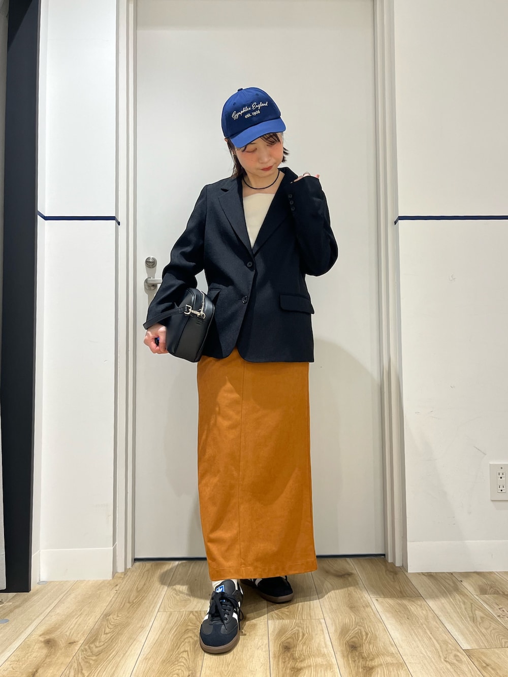 ブラック系のショルダーバッグ、ブラック系のその他アウター、ブラウン系のスカートを着用したレディースの春コーディネートの3枚目の写真