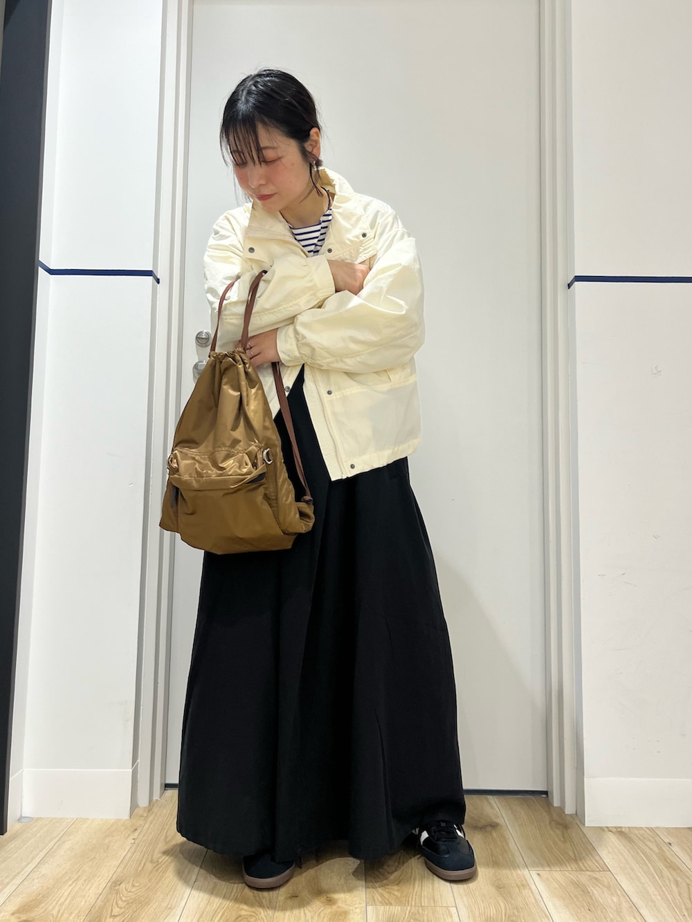 ブラック系のワンピース、ブラック系のスニーカー、ホワイト系のナイロンジャケットを着用したレディースの春コーディネートの2枚目の写真