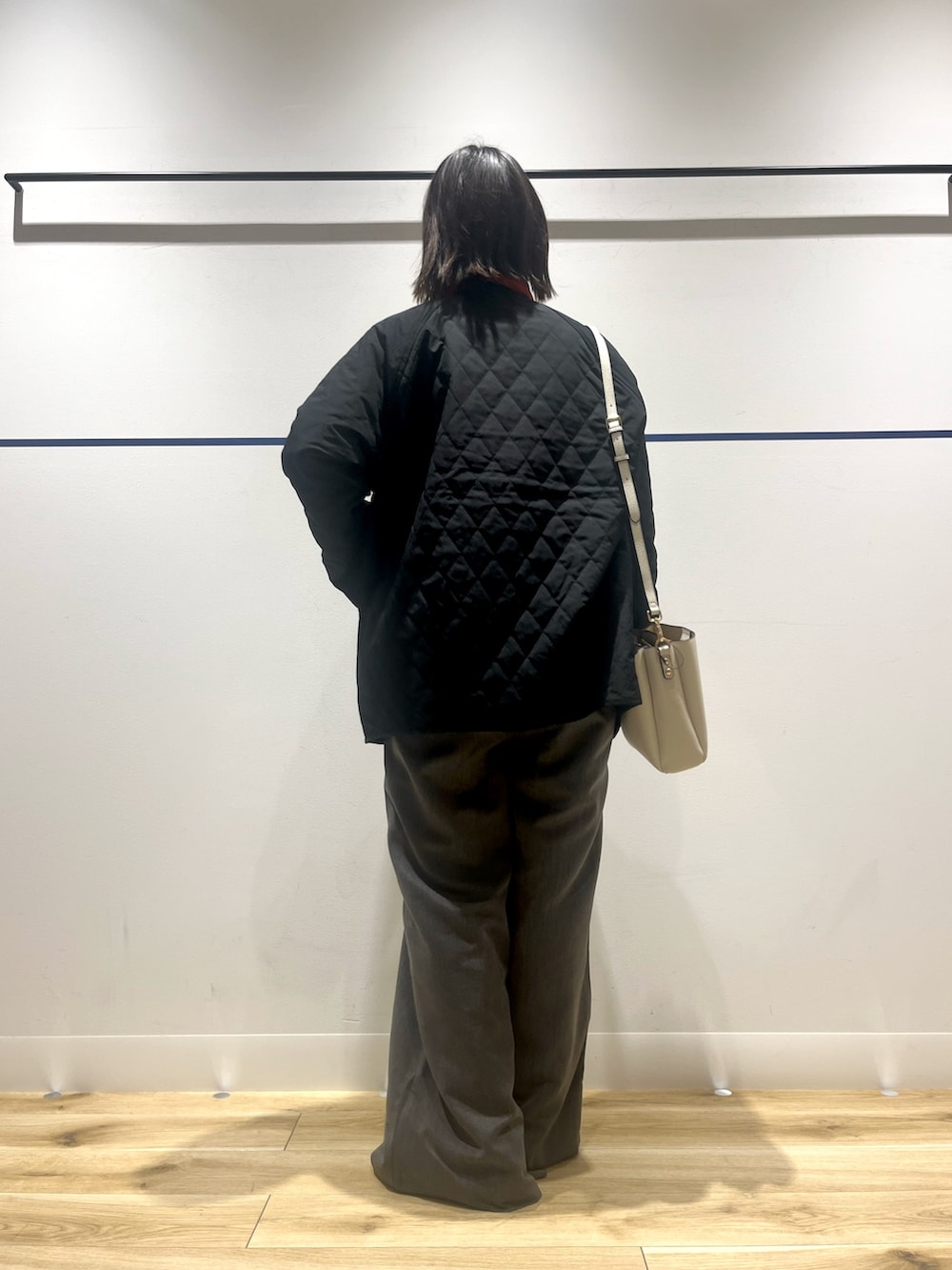 オレンジ系のニット/セーター、グレー系のその他パンツ、ホワイト系のショルダーバッグを着用したレディースの冬コーディネートの5枚目の写真