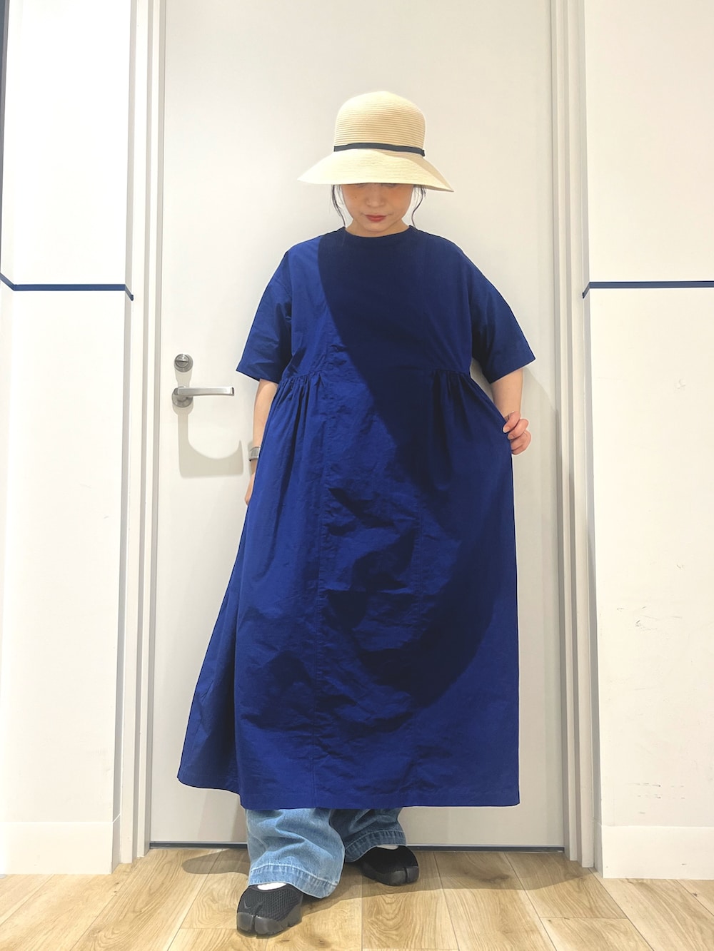 ブルー系のワンピース、ブルー系のトートバッグ、ブルー系のデニムパンツを着用したレディースの夏コーディネートの4枚目の写真