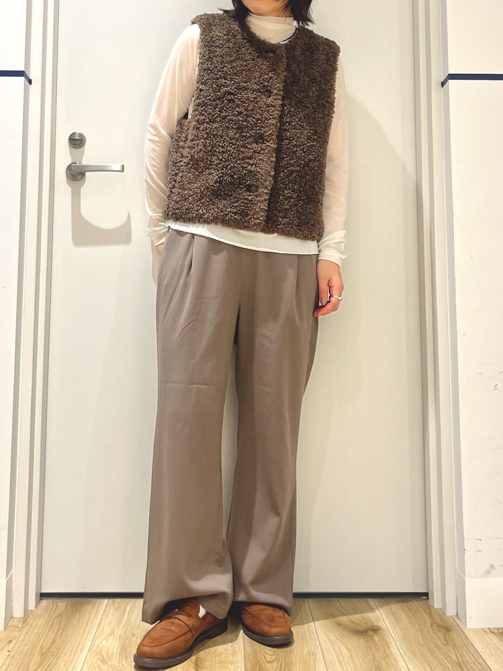 イエロー系のローファー、ベージュ系のその他パンツ、ブラウン系のダウンベストを着用したレディースの秋コーディネートの4枚目の写真