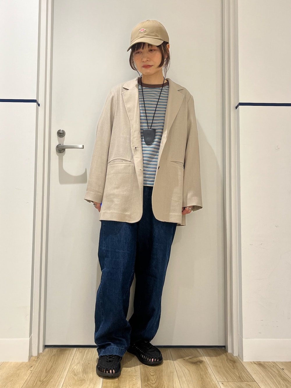 ブラック系のサンダル、ブルー系のデニムパンツ、レッド系のトートバッグを着用したレディースの春コーディネートの5枚目の写真