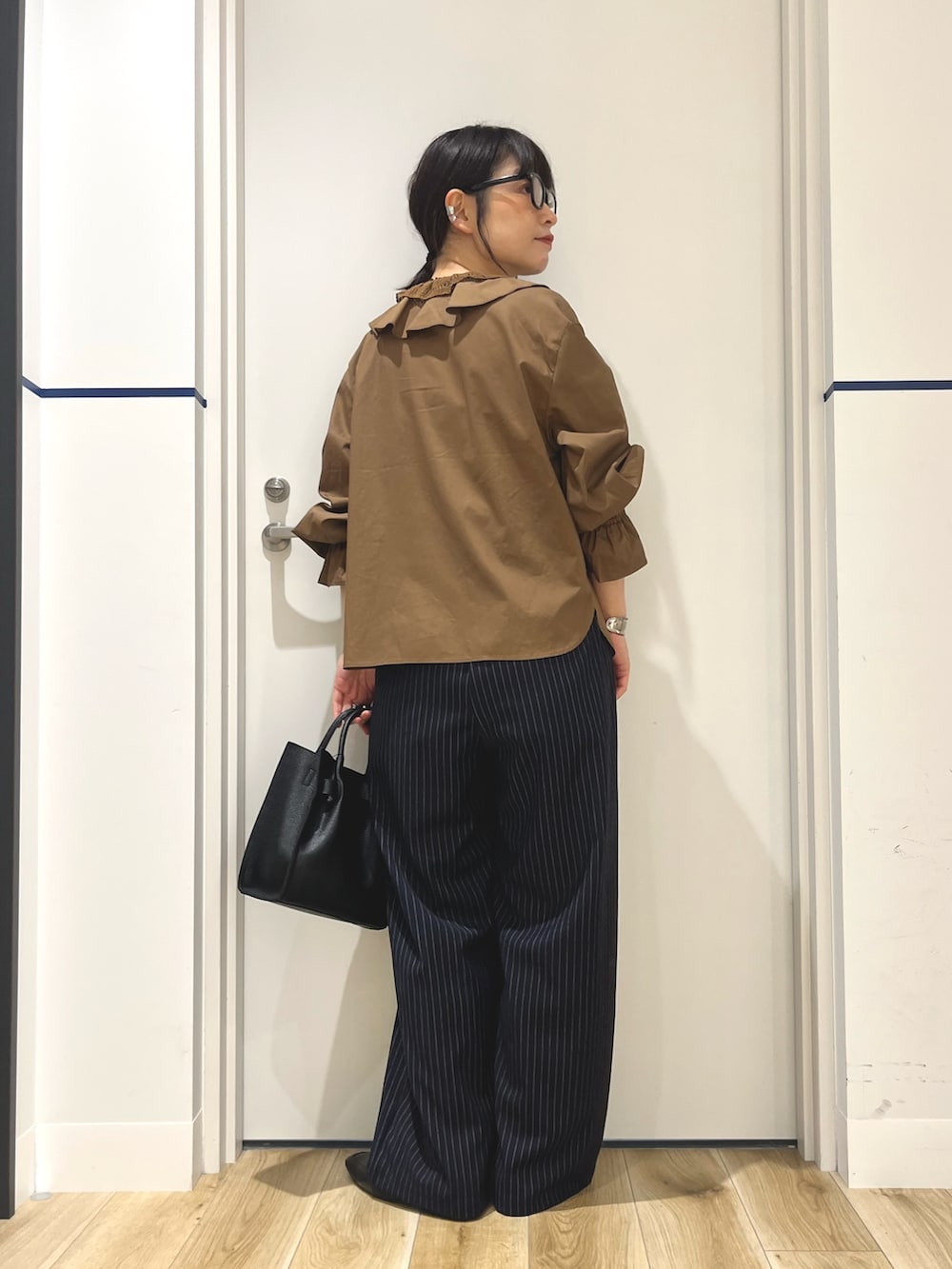 ブルー系のその他パンツ、ブラック系のハンドバッグ、ブラウン系のシャツ/ブラウスを着用したレディースの秋コーディネートの3枚目の写真