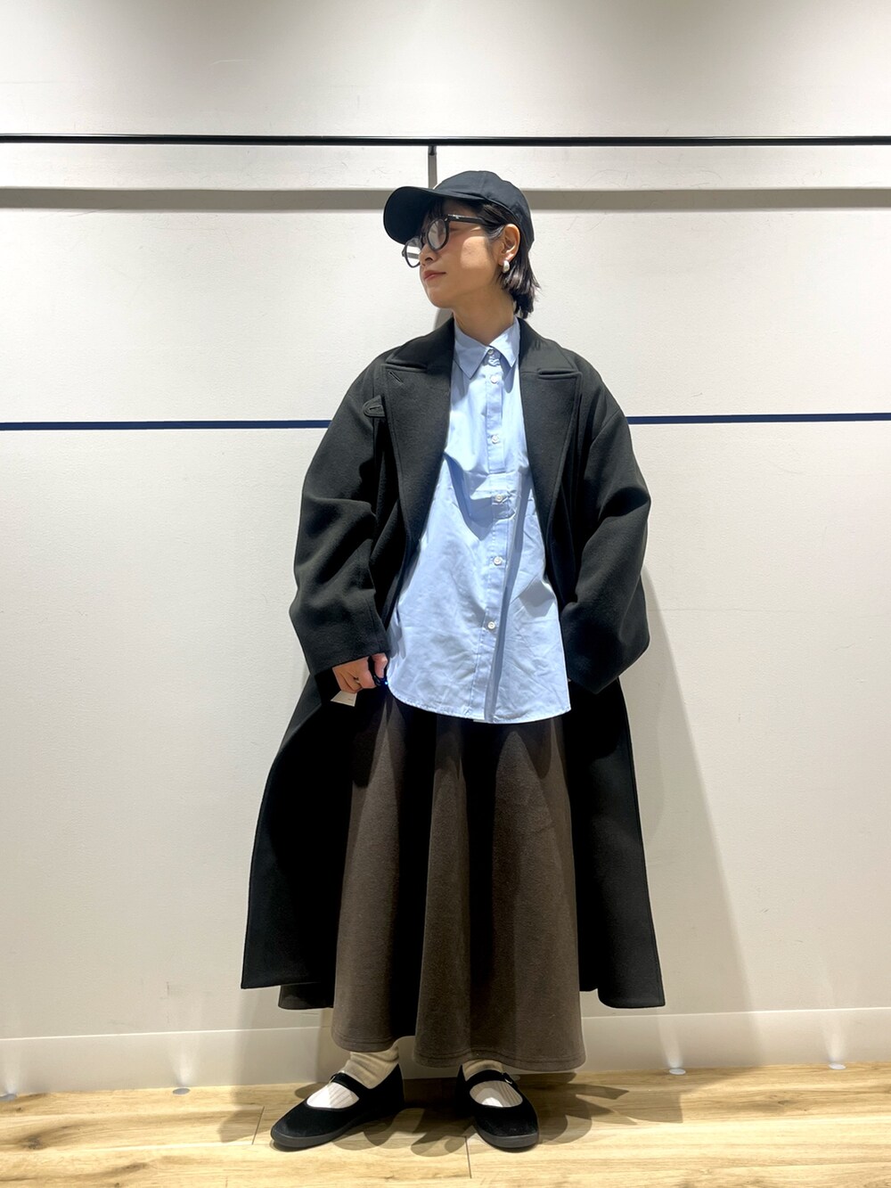 ブルー系のシャツ/ブラウス、グリーン系のチェスターコート、ブラウン系のスカートを着用したレディースの冬コーディネートの2枚目の写真