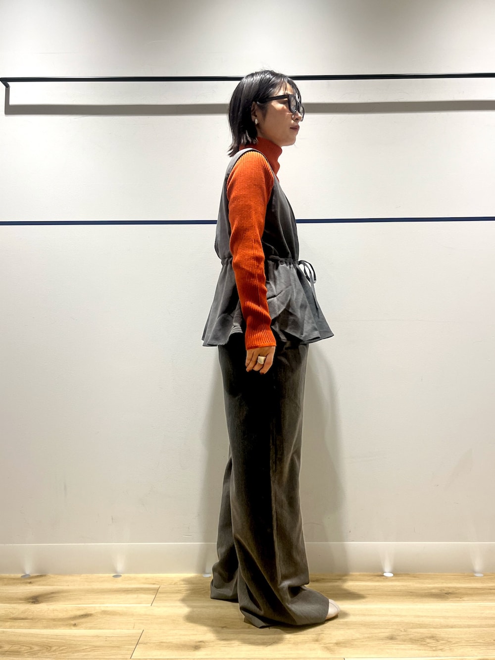 オレンジ系のニット/セーター、グレー系のその他パンツ、ホワイト系のショルダーバッグを着用したレディースの冬コーディネートの3枚目の写真