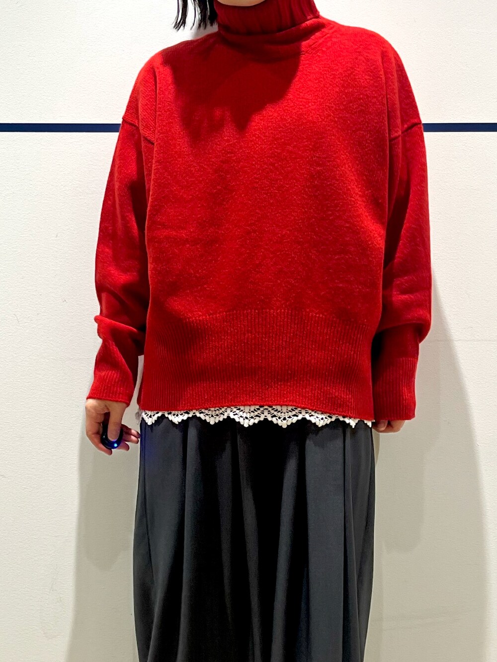 レッド系のニット/セーター、ブラック系のステンカラーコート、ホワイト系のTシャツ/カットソーを着用したレディースの冬コーディネートの7枚目の写真