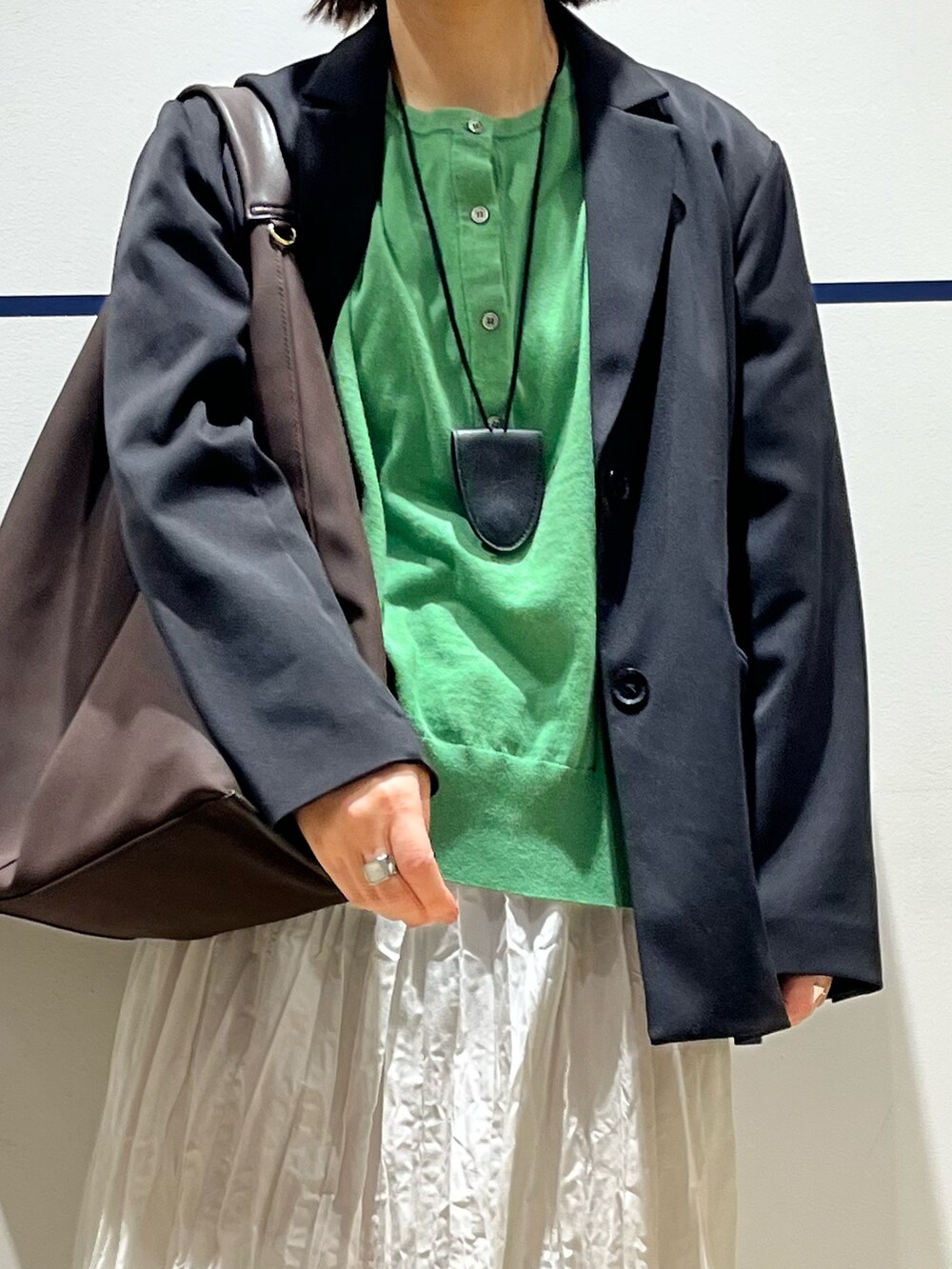 ブラウン系のトートバッグ、グリーン系のニット/セーター、ブラック系のその他アウターを着用したレディースの冬コーディネートの4枚目の写真