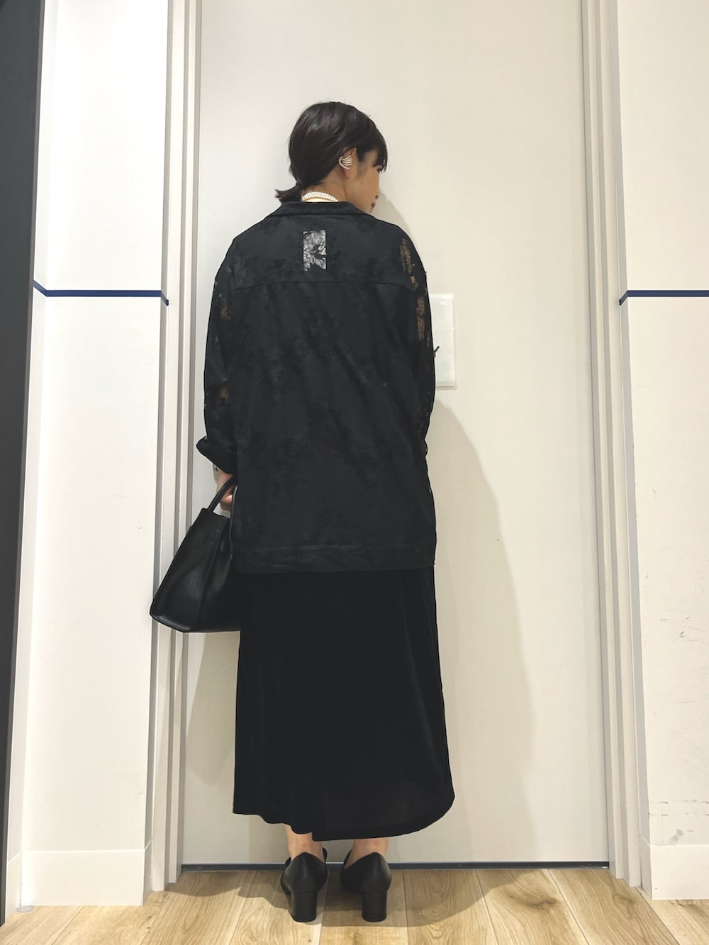 ブラック系のパンプス、ブラック系のハンドバッグ、ブラック系のシャツ/ブラウスを着用したレディースの秋コーディネートの2枚目の写真