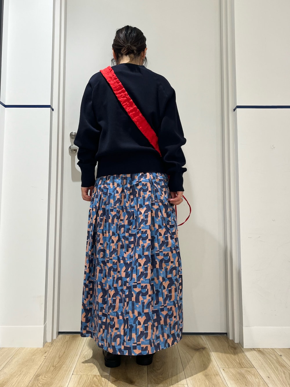 ブラック系のローファー、ブルー系のスカート、レッド系のショルダーバッグを着用したレディースの春コーディネートの3枚目の写真