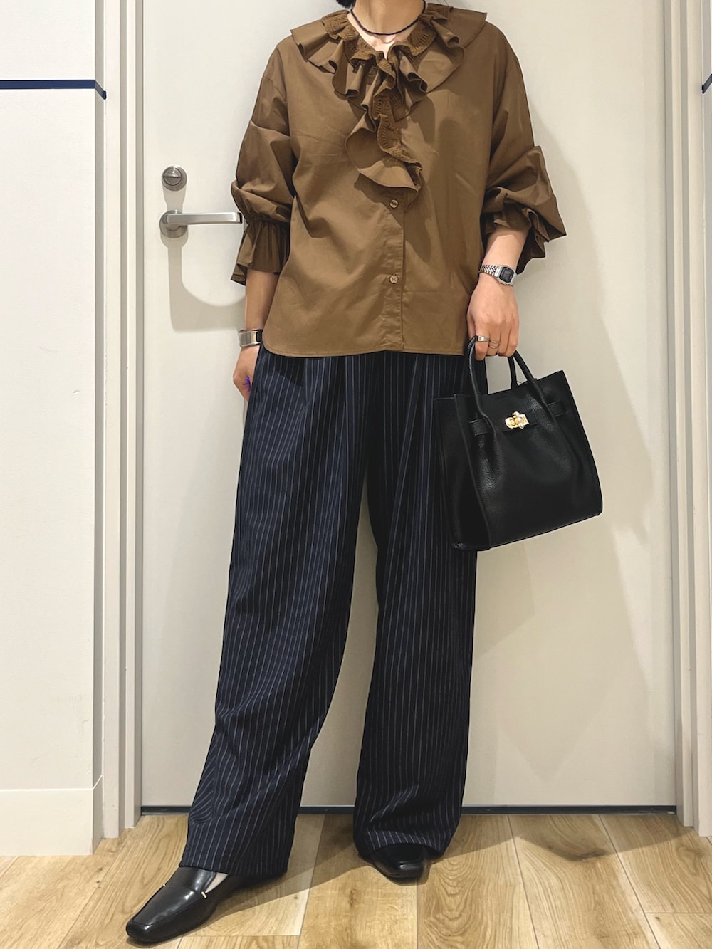 ブルー系のその他パンツ、ブラック系のハンドバッグ、ブラウン系のシャツ/ブラウスを着用したレディースの秋コーディネートの4枚目の写真