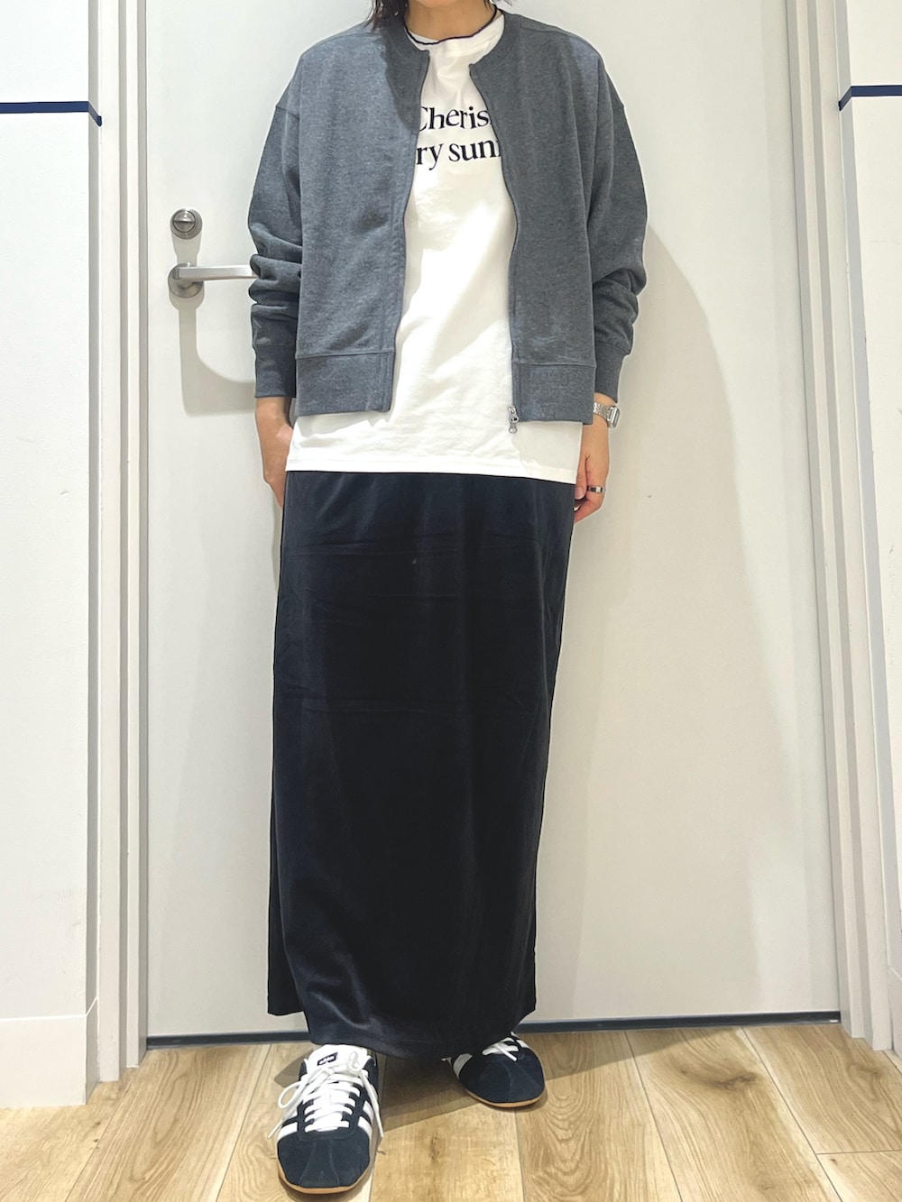 ブラック系のスニーカー、ブラック系のスカート、ホワイト系のTシャツ/カットソーを着用したレディースの秋コーディネートの4枚目の写真