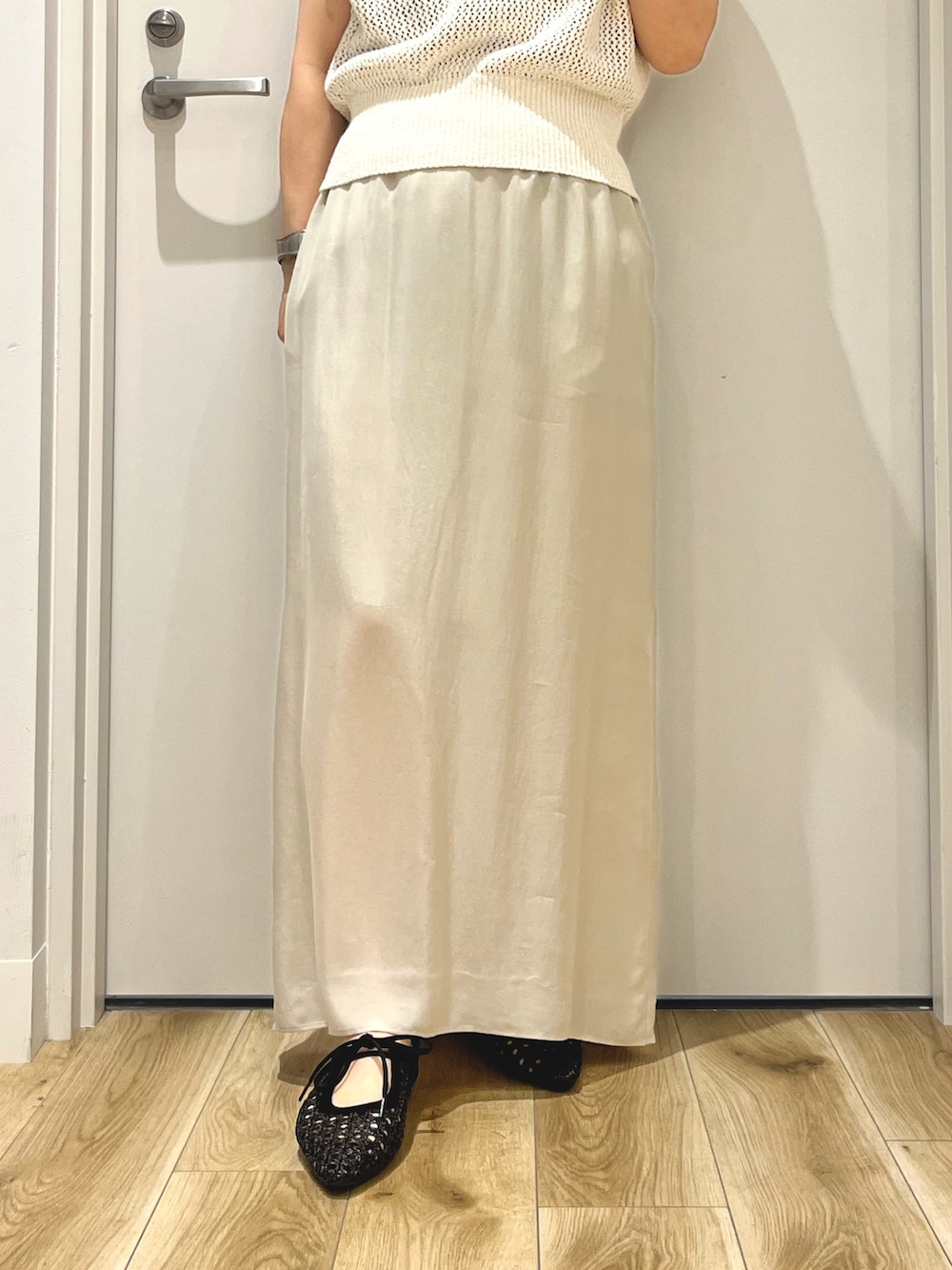 ベージュ系のスカート、ホワイト系のニット/セーター、ブラック系のパンプスを着用したレディースの夏コーディネートの3枚目の写真
