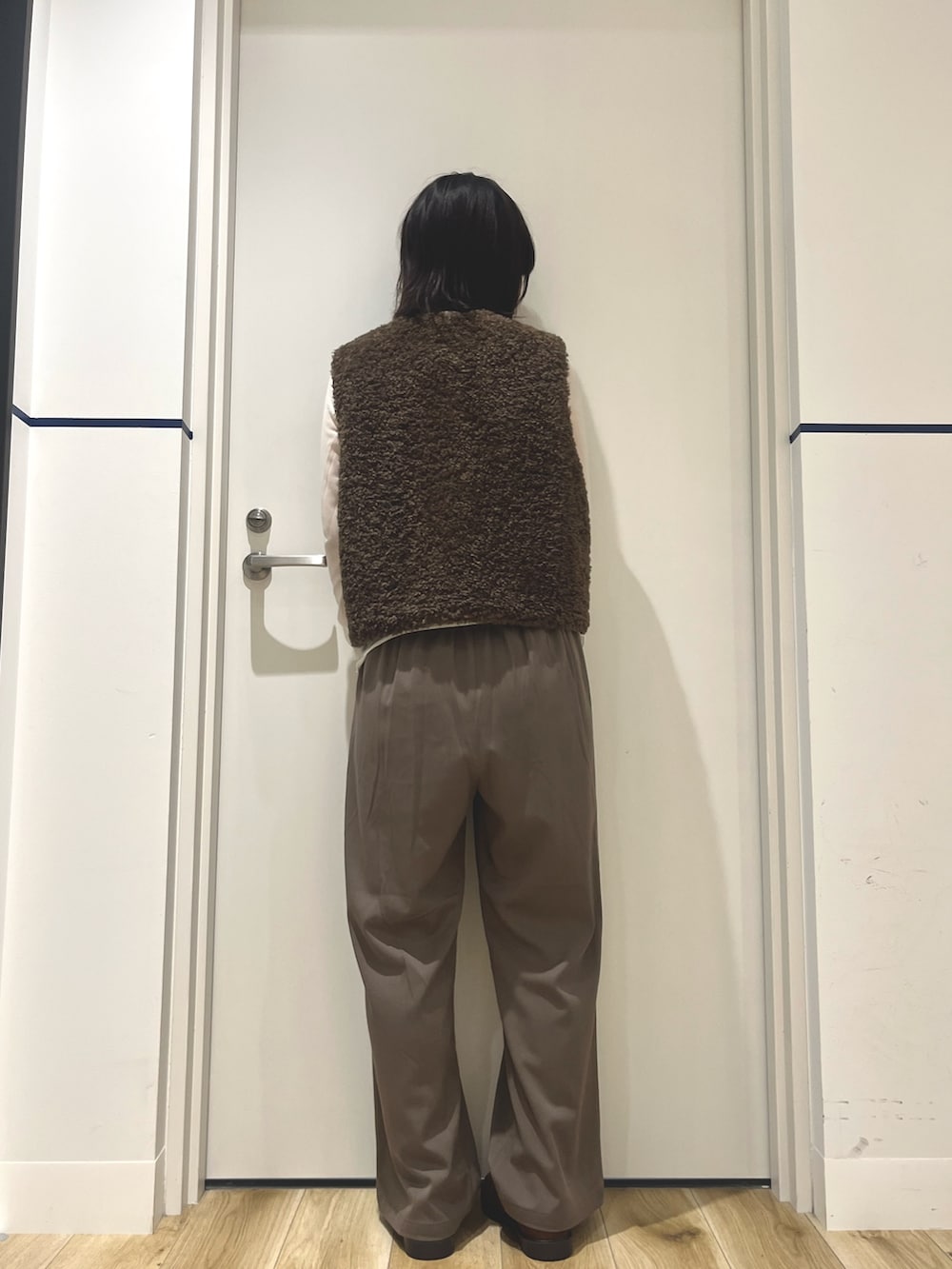 イエロー系のローファー、ベージュ系のその他パンツ、ブラウン系のダウンベストを着用したレディースの秋コーディネートの3枚目の写真