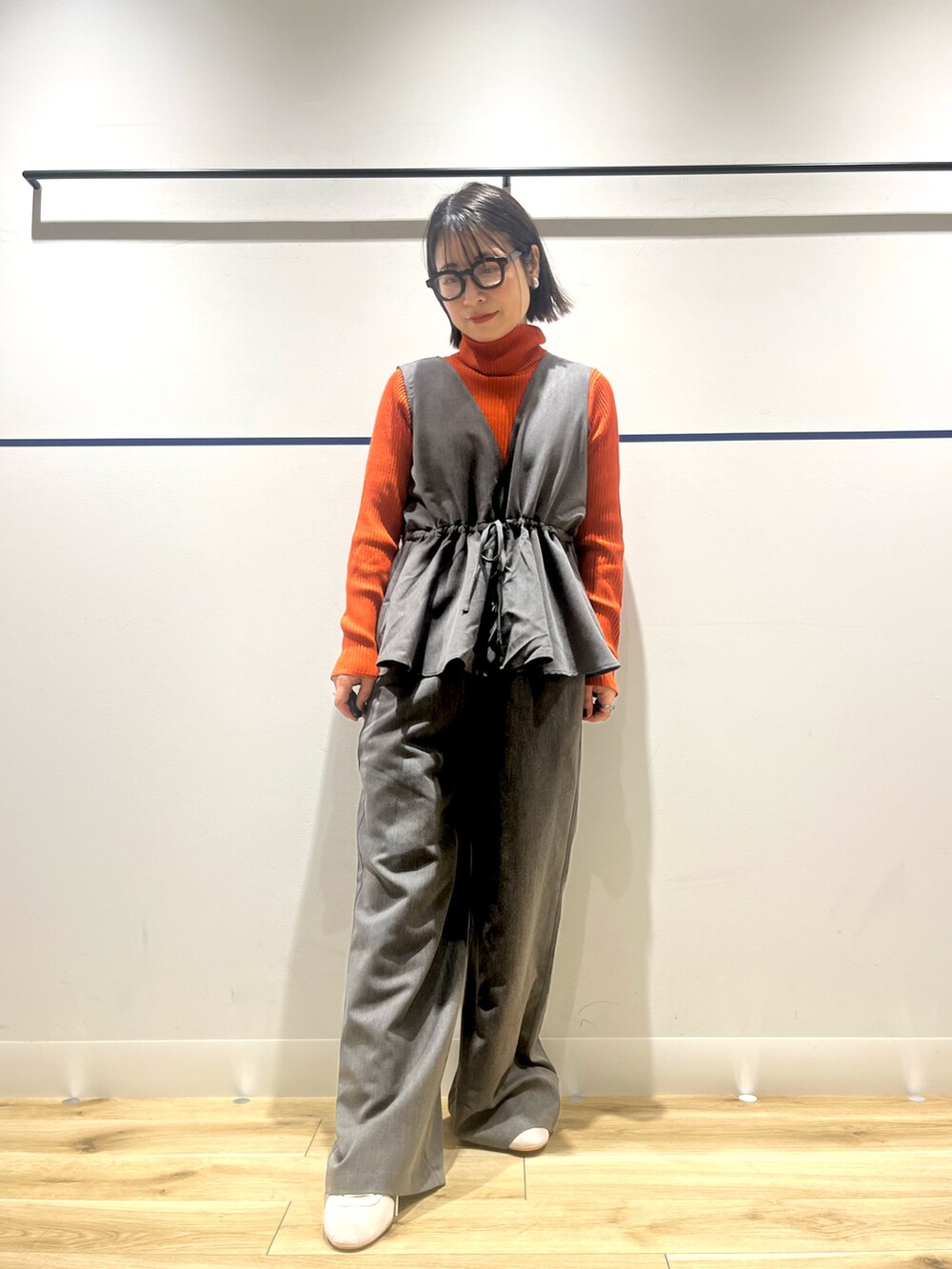 オレンジ系のニット/セーター、グレー系のその他パンツ、ホワイト系のショルダーバッグを着用したレディースの冬コーディネートの2枚目の写真