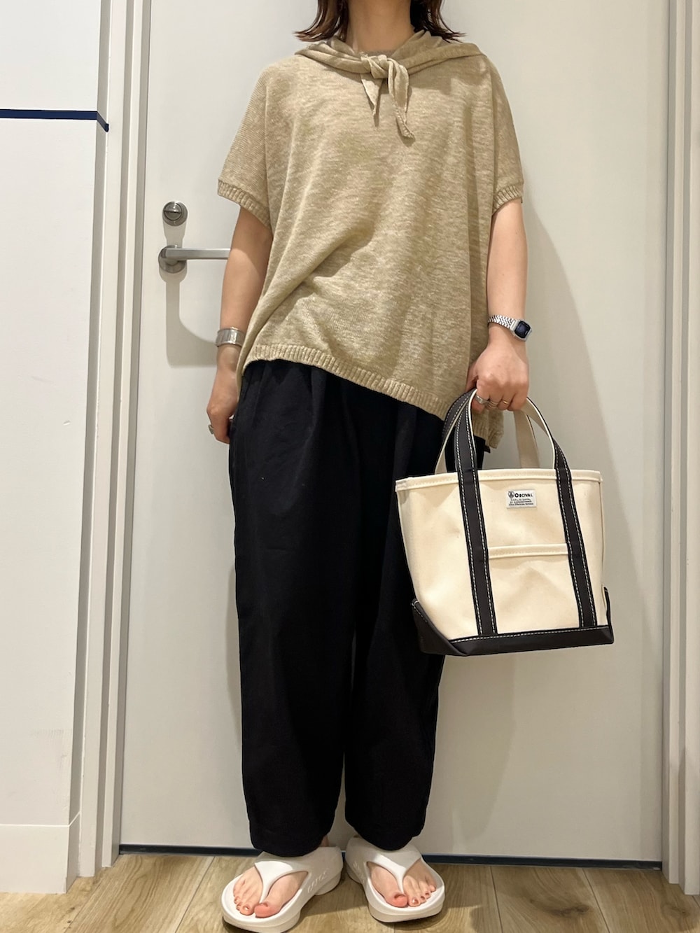 グレー系のトートバッグ、ホワイト系のサンダル、ブラック系のその他パンツを着用したレディースの春コーディネートの6枚目の写真