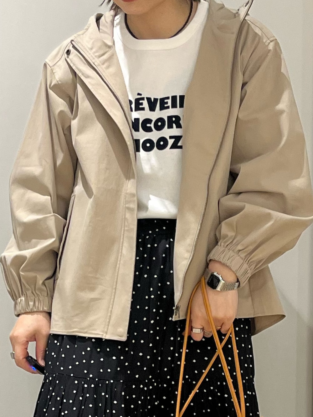 ベージュ系のその他アウター、ブラック系のスカート、オレンジ系のショルダーバッグを着用したレディースの春コーディネートの3枚目の写真