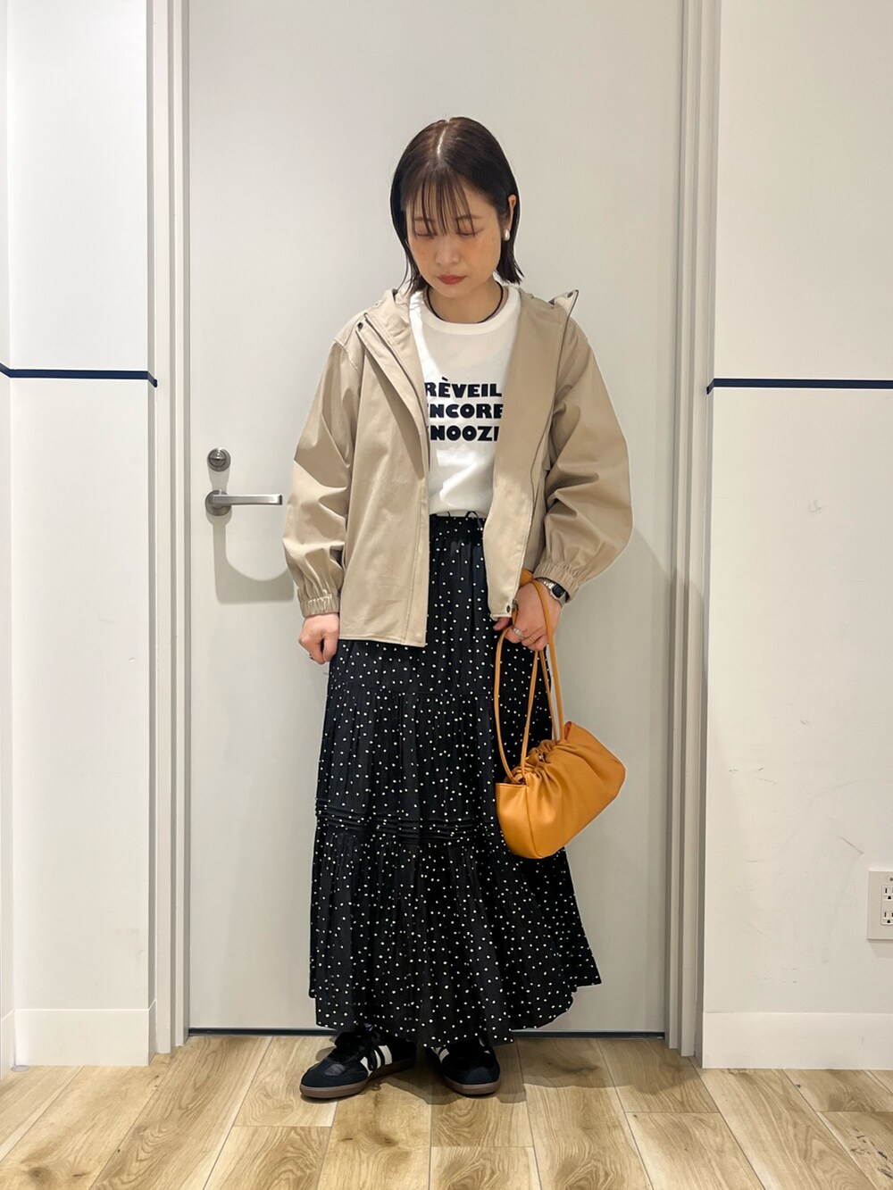 ベージュ系のその他アウター、ブラック系のスカート、オレンジ系のショルダーバッグを着用したレディースの春コーディネートの5枚目の写真