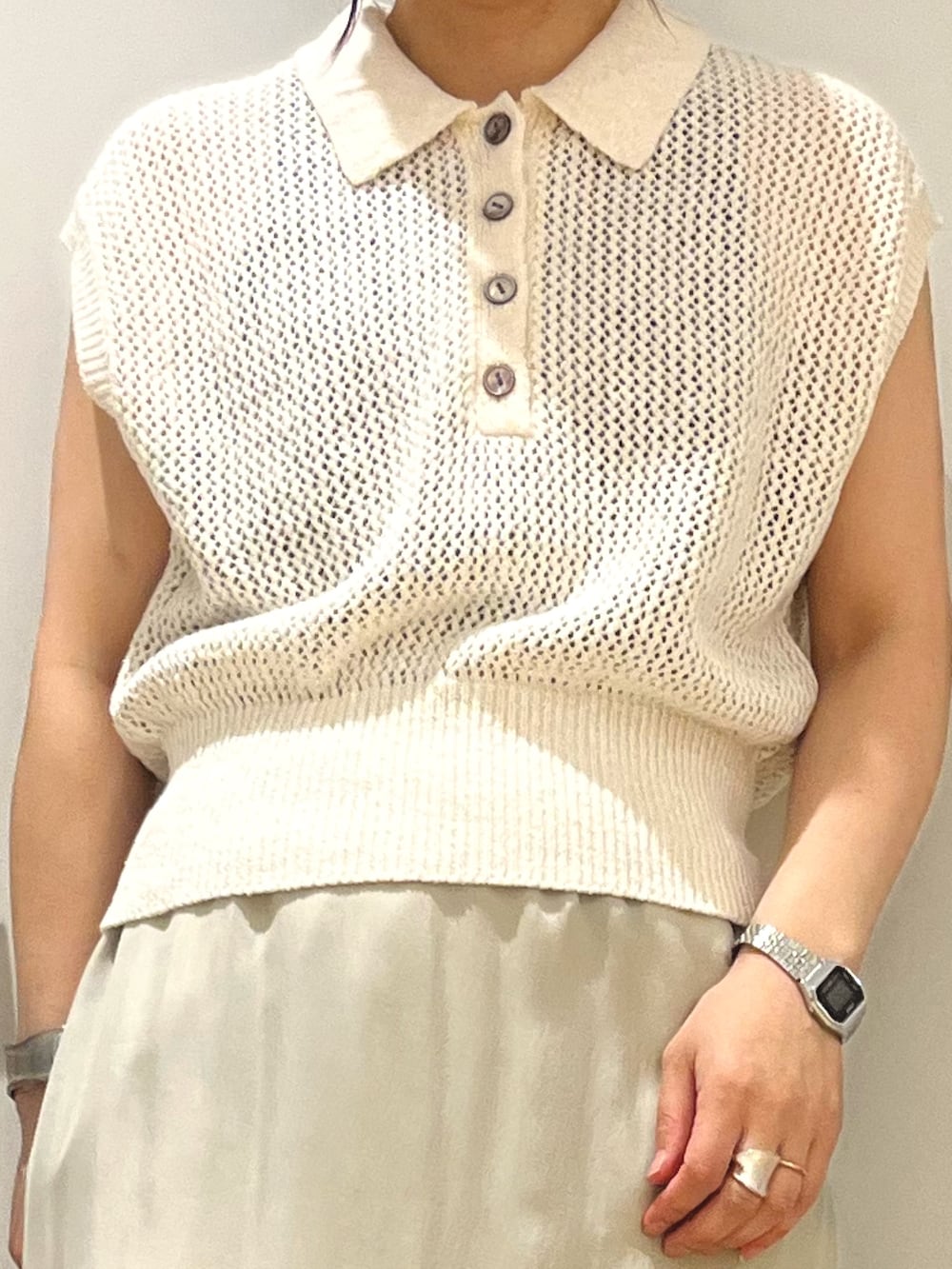 ベージュ系のスカート、ホワイト系のニット/セーター、ブラック系のパンプスを着用したレディースの夏コーディネートの2枚目の写真