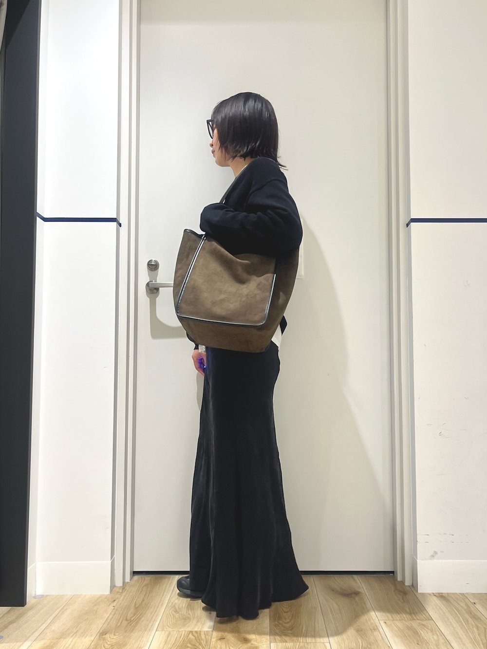 ブラック系のニット/セーター、グリーン系のトートバッグ、ホワイト系のTシャツ/カットソーを着用したレディースの秋コーディネートの2枚目の写真