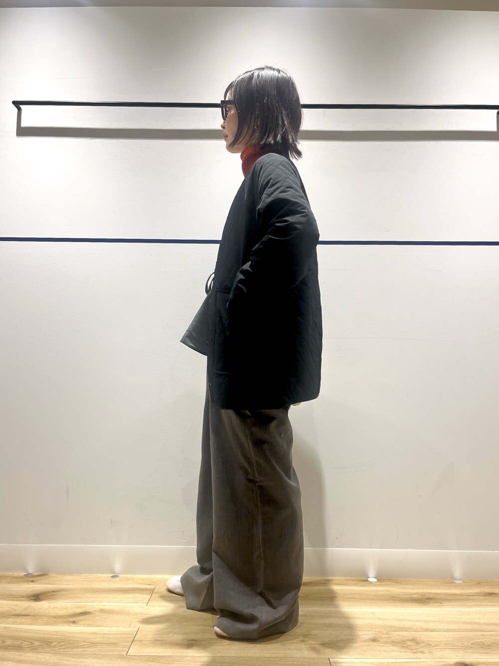 オレンジ系のニット/セーター、グレー系のその他パンツ、ホワイト系のショルダーバッグを着用したレディースの冬コーディネートの6枚目の写真