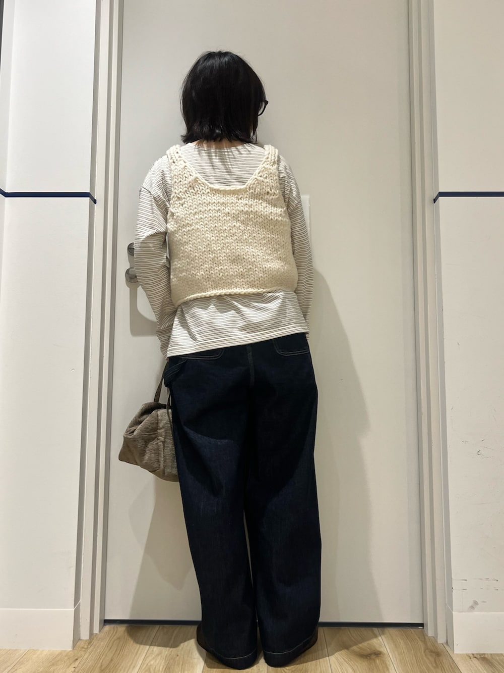 ブルー系のデニムパンツ、グリーン系のハンドバッグ、ホワイト系のTシャツ/カットソーを着用したレディースの秋コーディネートの2枚目の写真