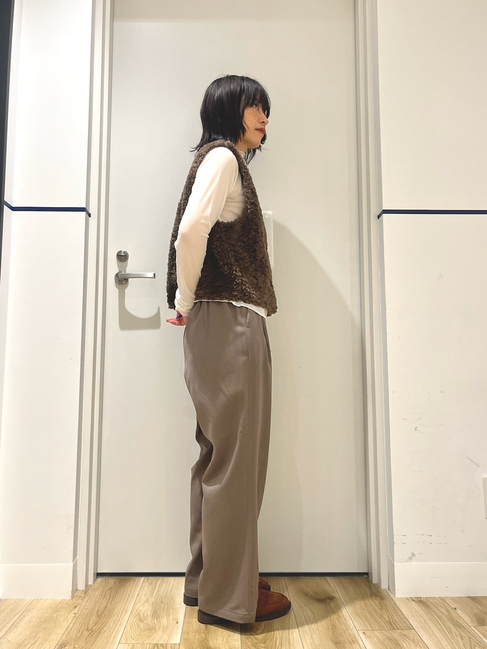 イエロー系のローファー、ベージュ系のその他パンツ、ブラウン系のダウンベストを着用したレディースの秋コーディネートの2枚目の写真