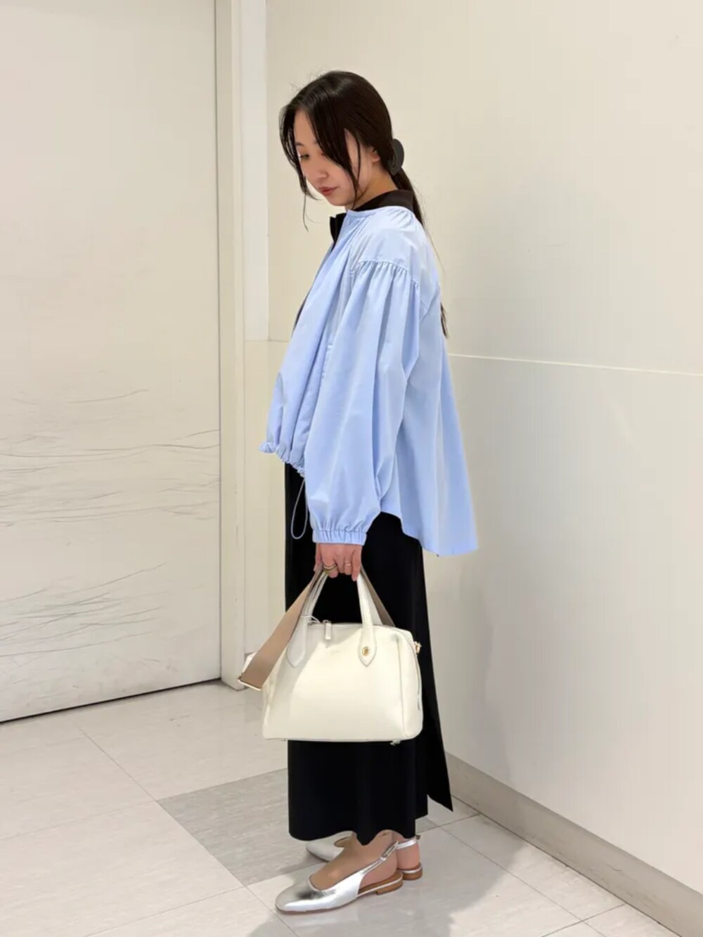 ベージュ系のボストンバッグ、シルバー系のパンプス、ブルー系のブルゾンを着用したレディースの春コーディネートの2枚目の写真